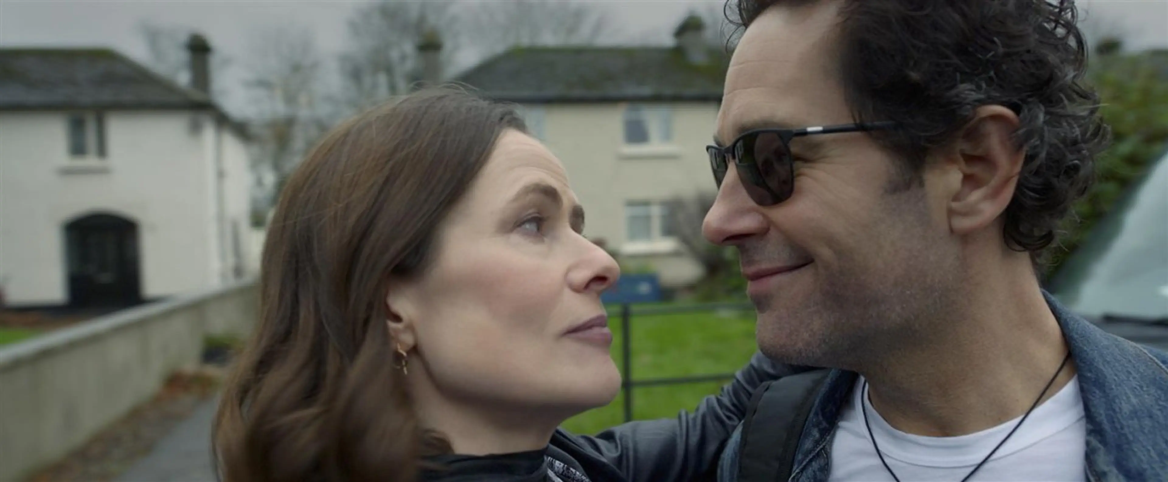 Rachel and Rick wear sunglasses as they stand close together outdoors.