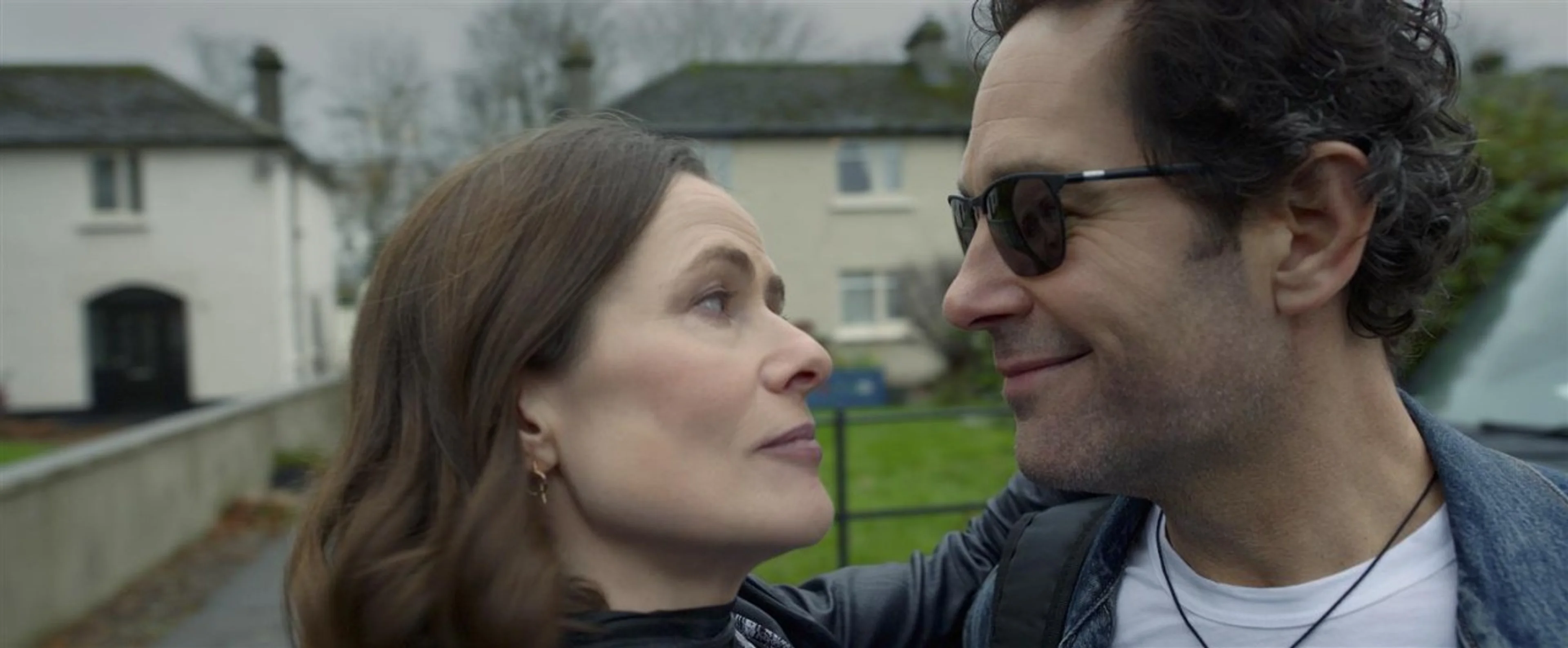 Rachel and Rick wear sunglasses as they stand close together outdoors.