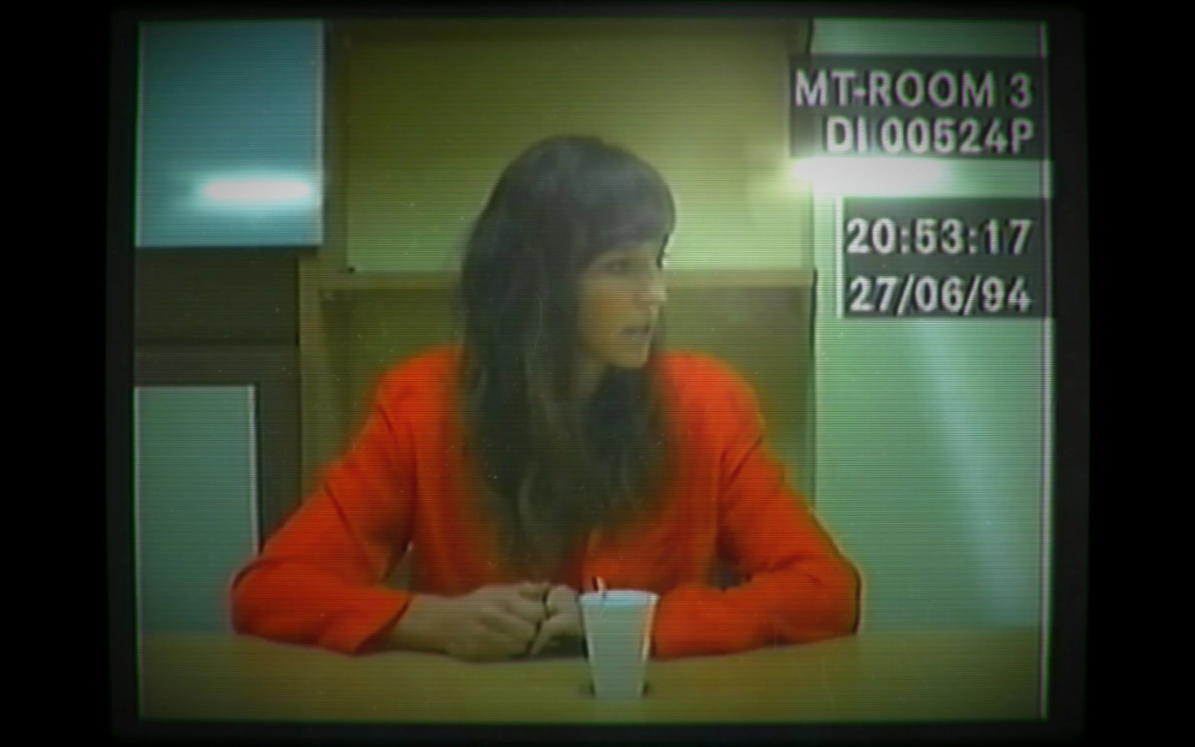 The Her Story interview subject wears a red blouse in a police-room recording, with a date and time stamp at top right.