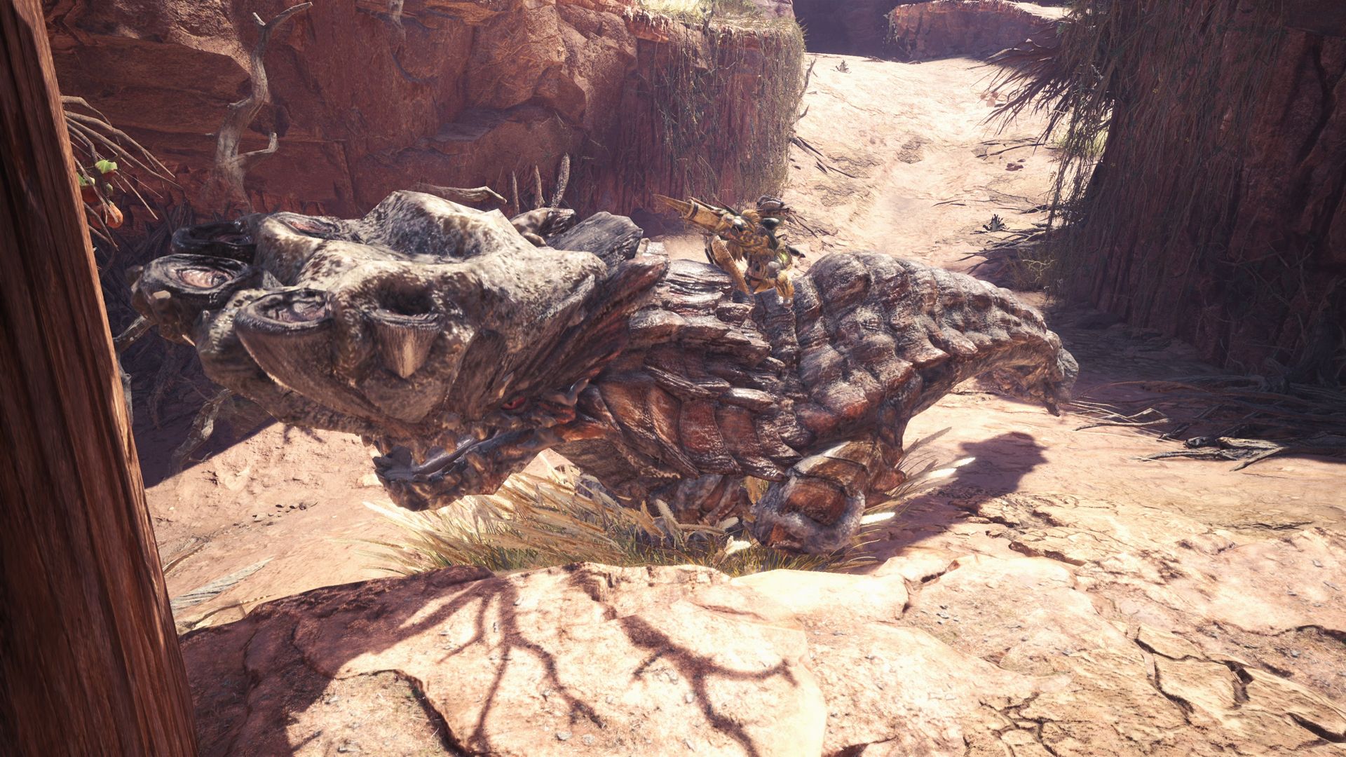 A hunter confronts a large creature on sandy ground in Monster Hunter: World.