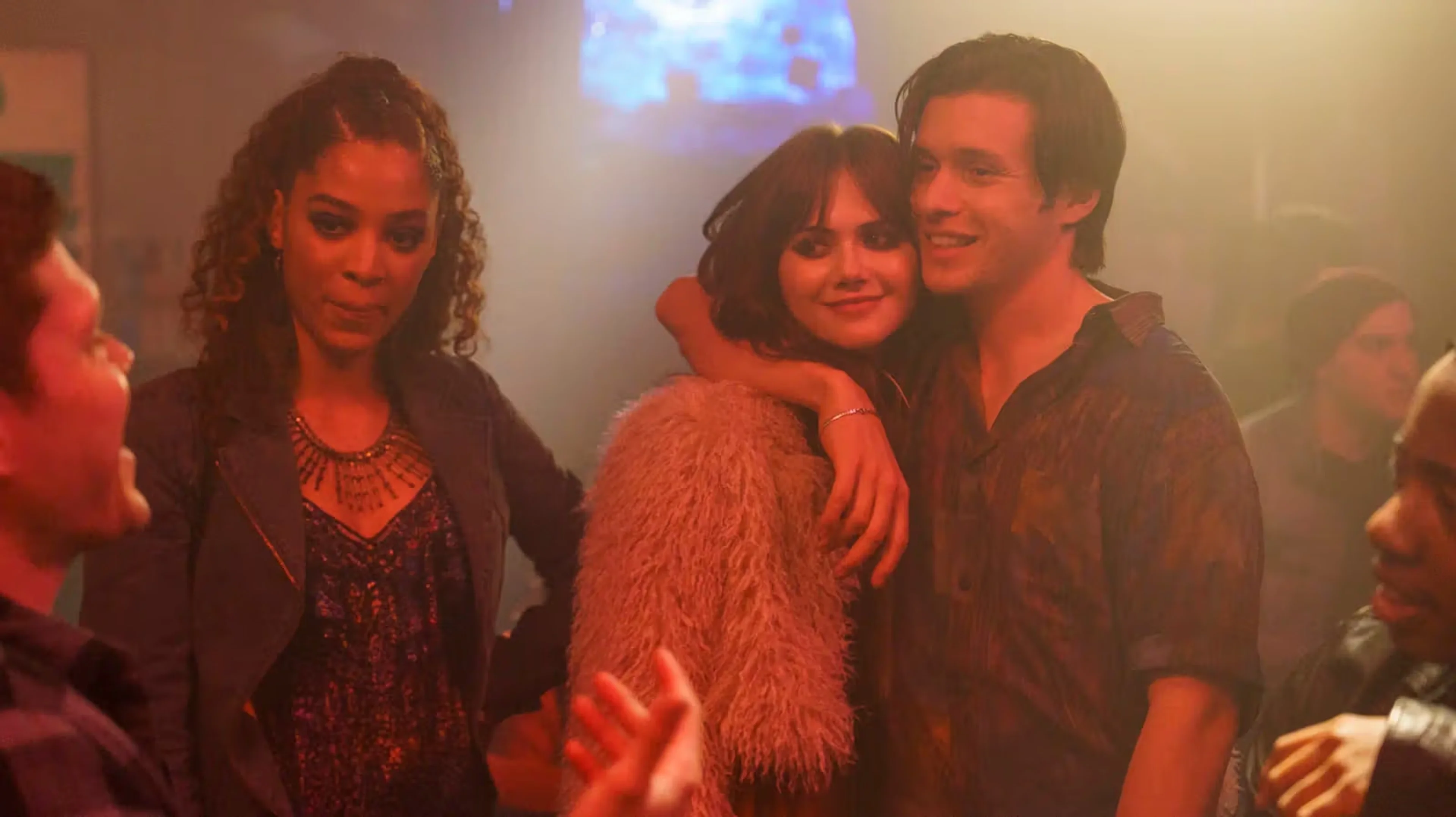 Harper and Charlie stand together at a crowded party.