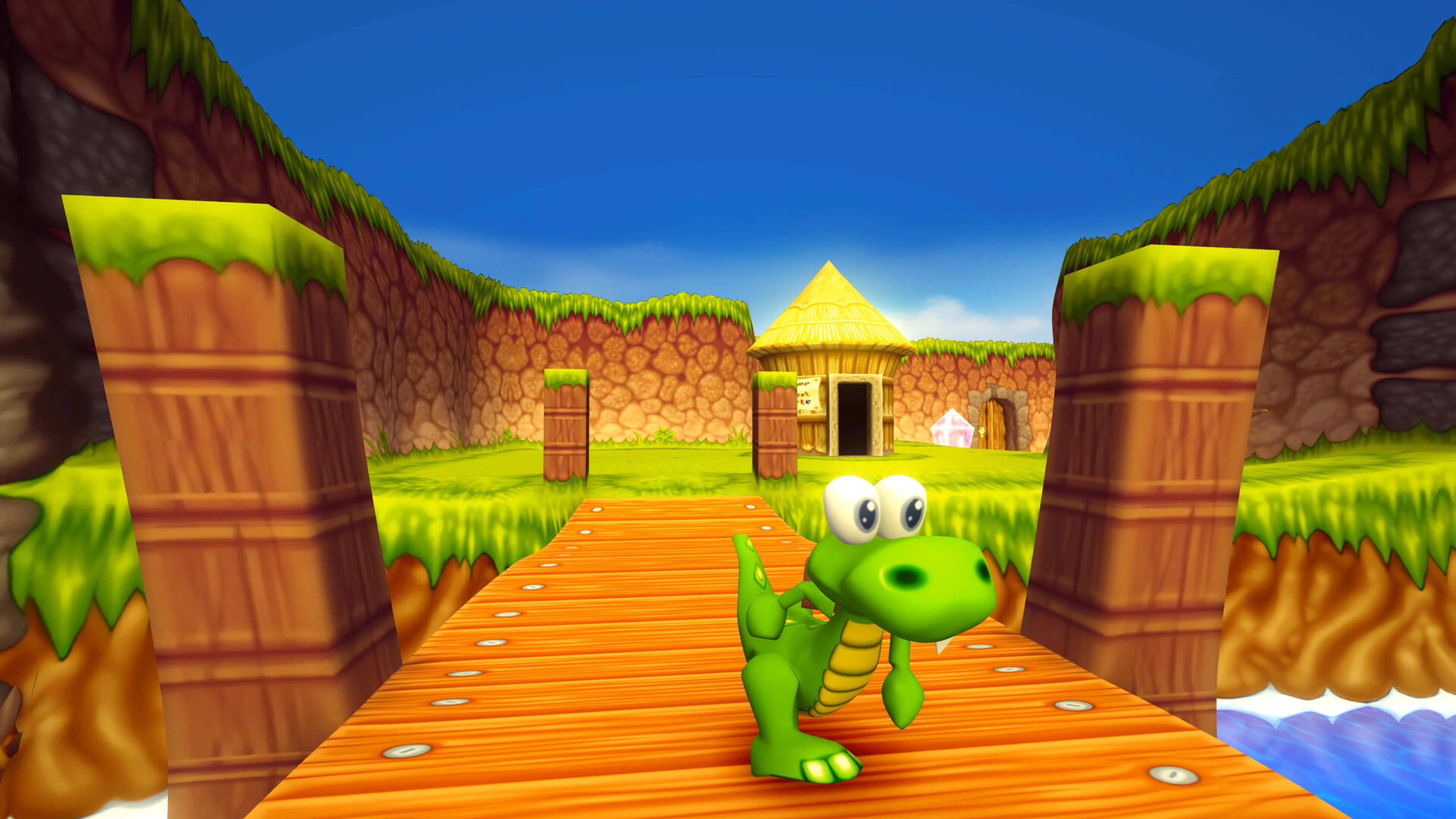 Croc stands on a wooden bridge between grassy walls and carved pillars in Croc 2.