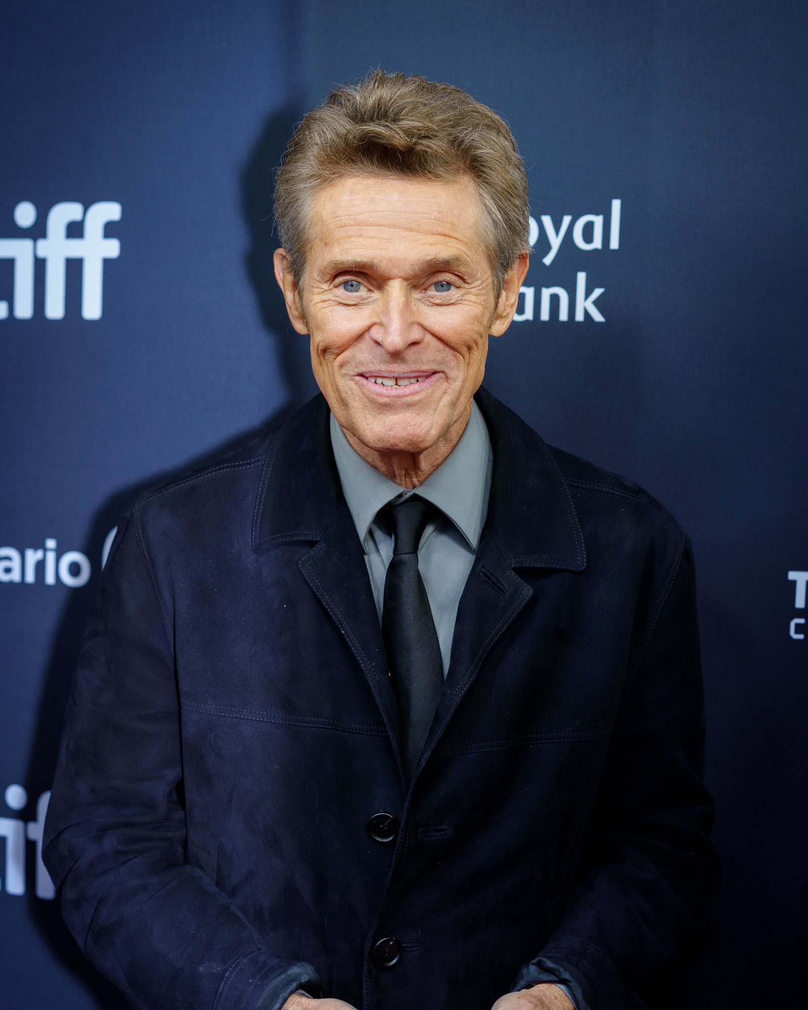 Willem Dafoe smiles on the 2024 Toronto International Film Festival red carpet.