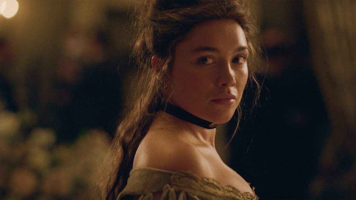 Florence Pugh as Cathy Ames looks over her shoulder in a warmly lit ballroom in East of Eden.