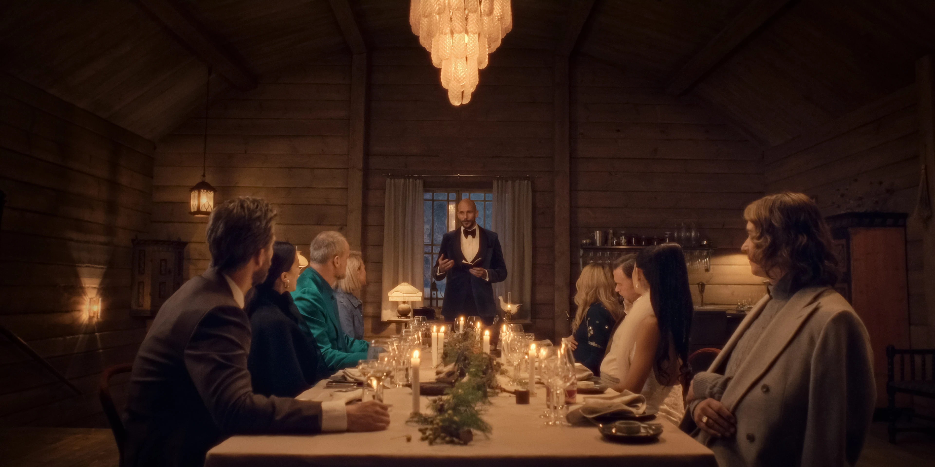 Friends sit around a long candlelit dinner table at a Swedish farmhouse.