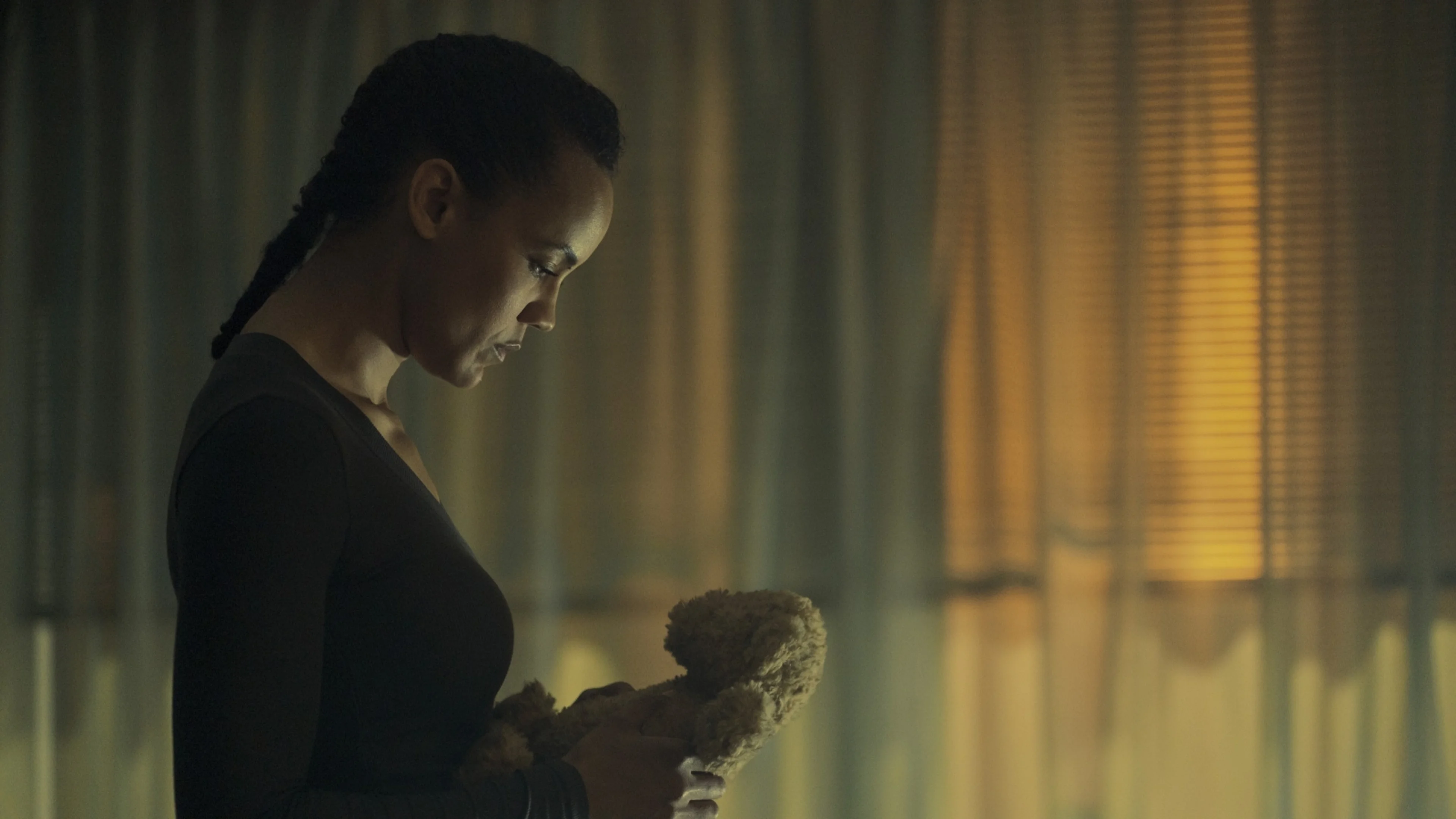 Frances Neagley looks down at a teddy bear during a quiet scene from the official trailer.