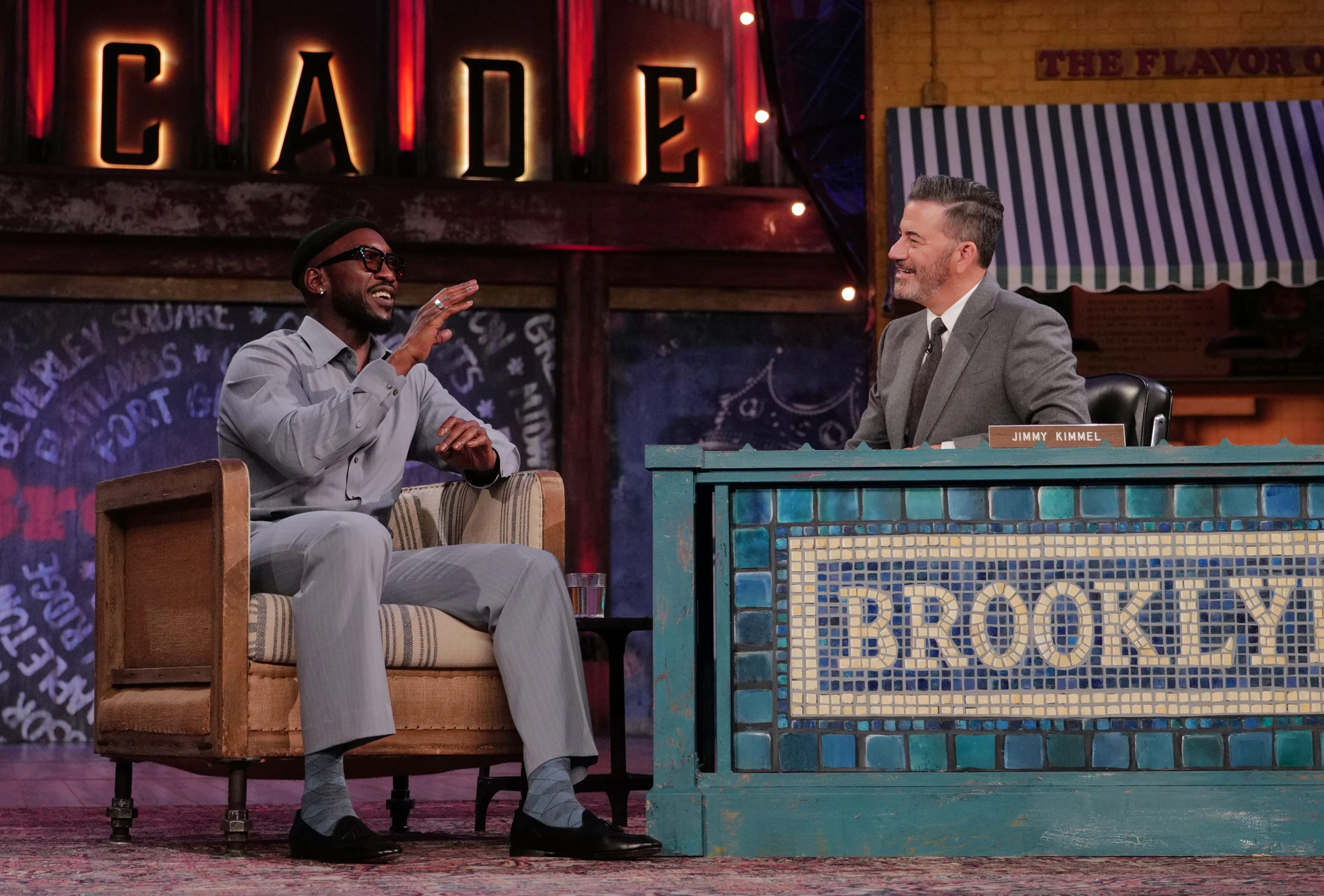 Mahershala Ali raises a hand as he talks with Jimmy Kimmel on the Brooklyn set.
