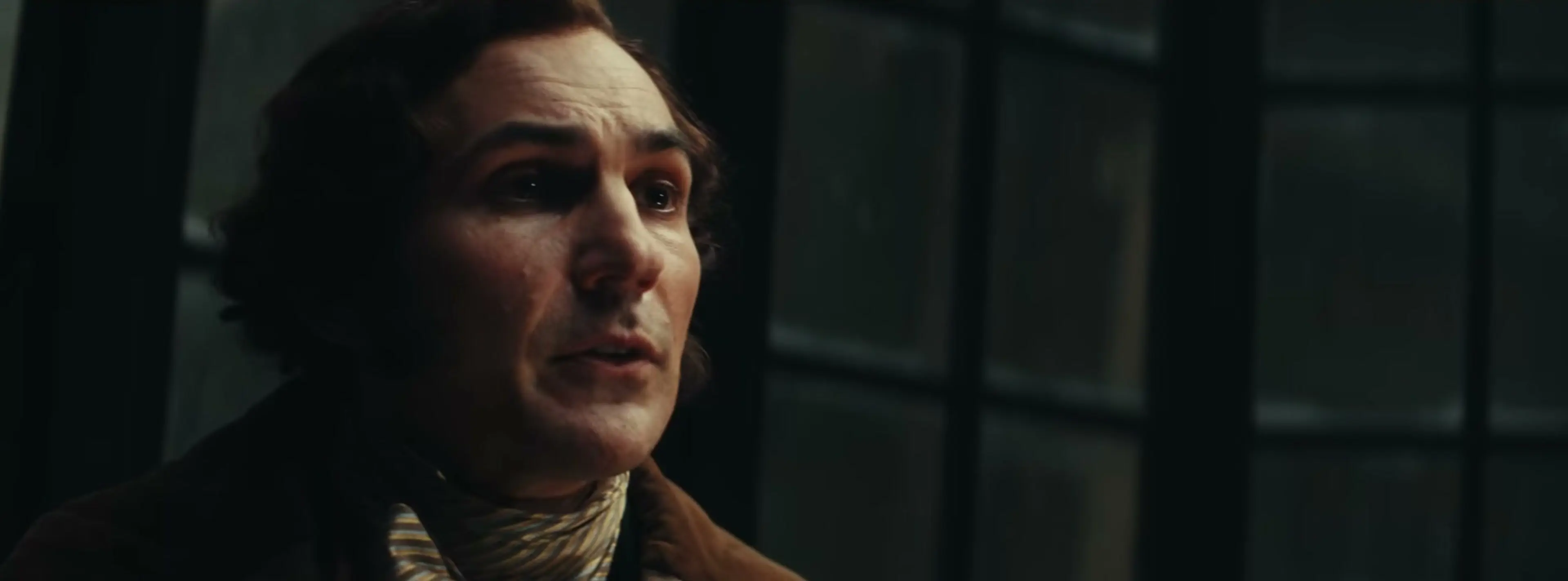 Sam Claflin in a striped scarf and dark coat in Ebenezer.