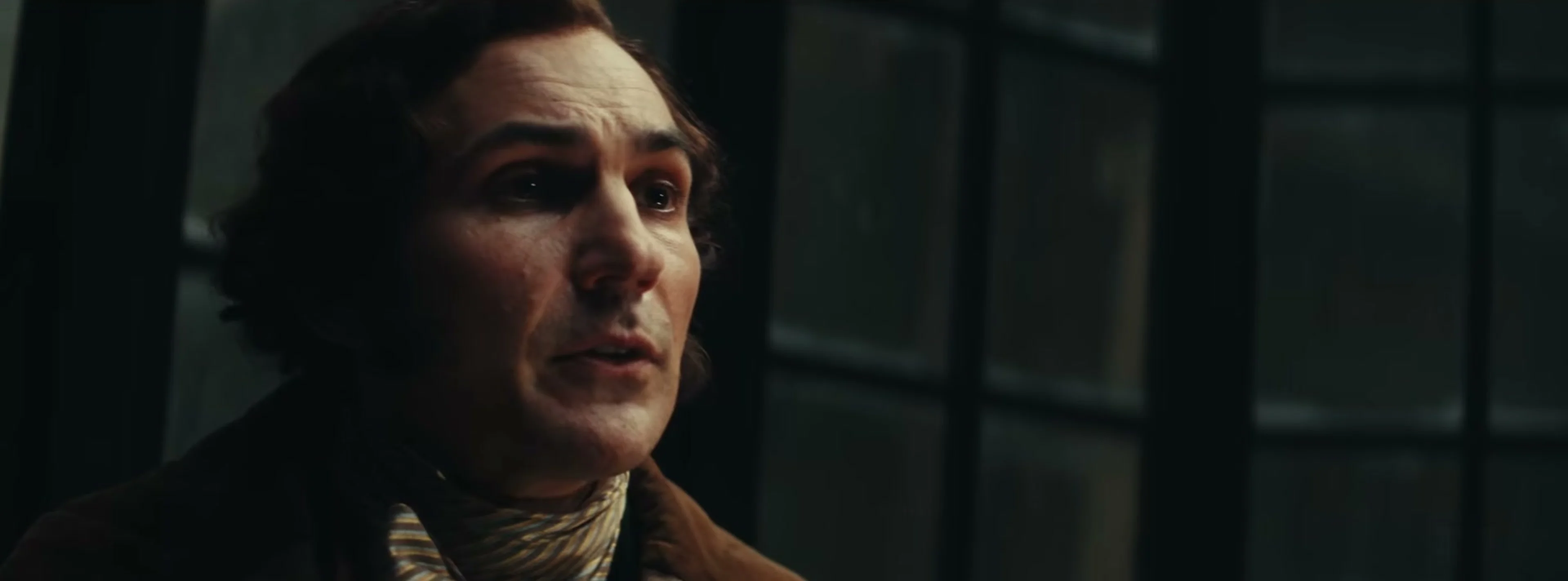 Sam Claflin in a striped scarf and dark coat in Ebenezer.