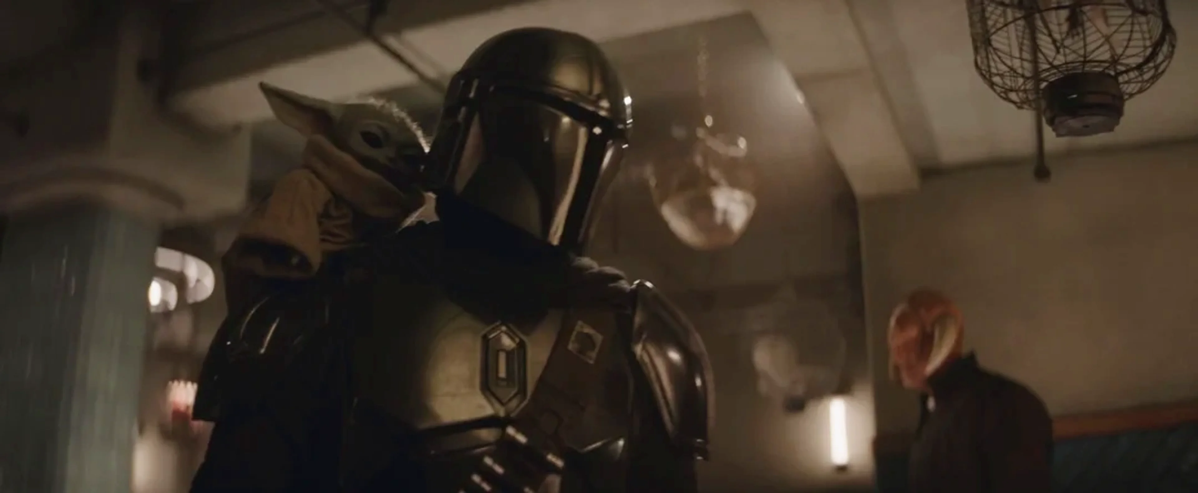 The Mandalorian holding Grogu in an official movie image