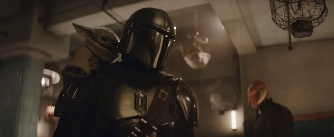 The Mandalorian holding Grogu in an official movie image