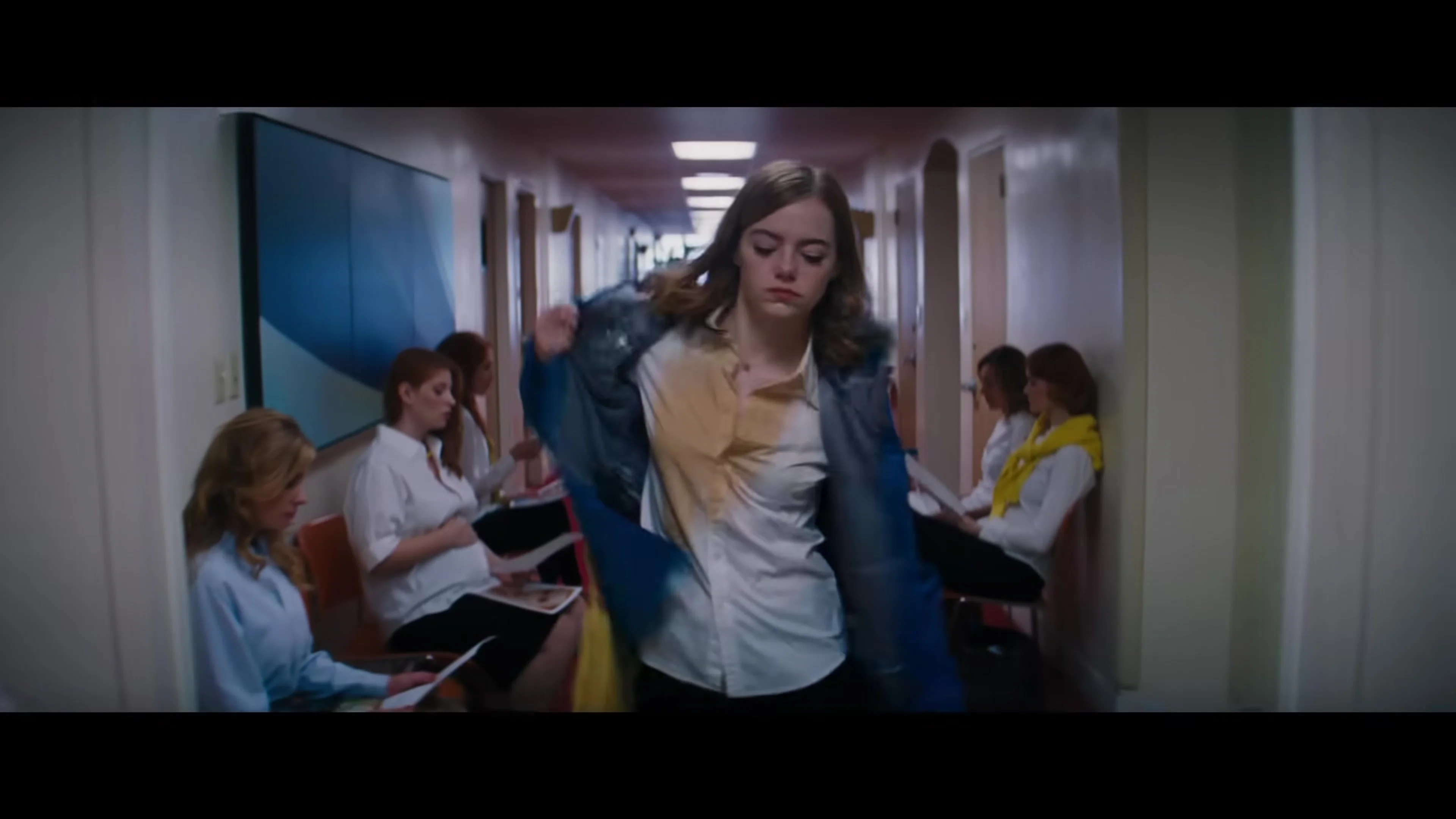 Emma Stone as Mia walks through an audition hallway in La La Land.