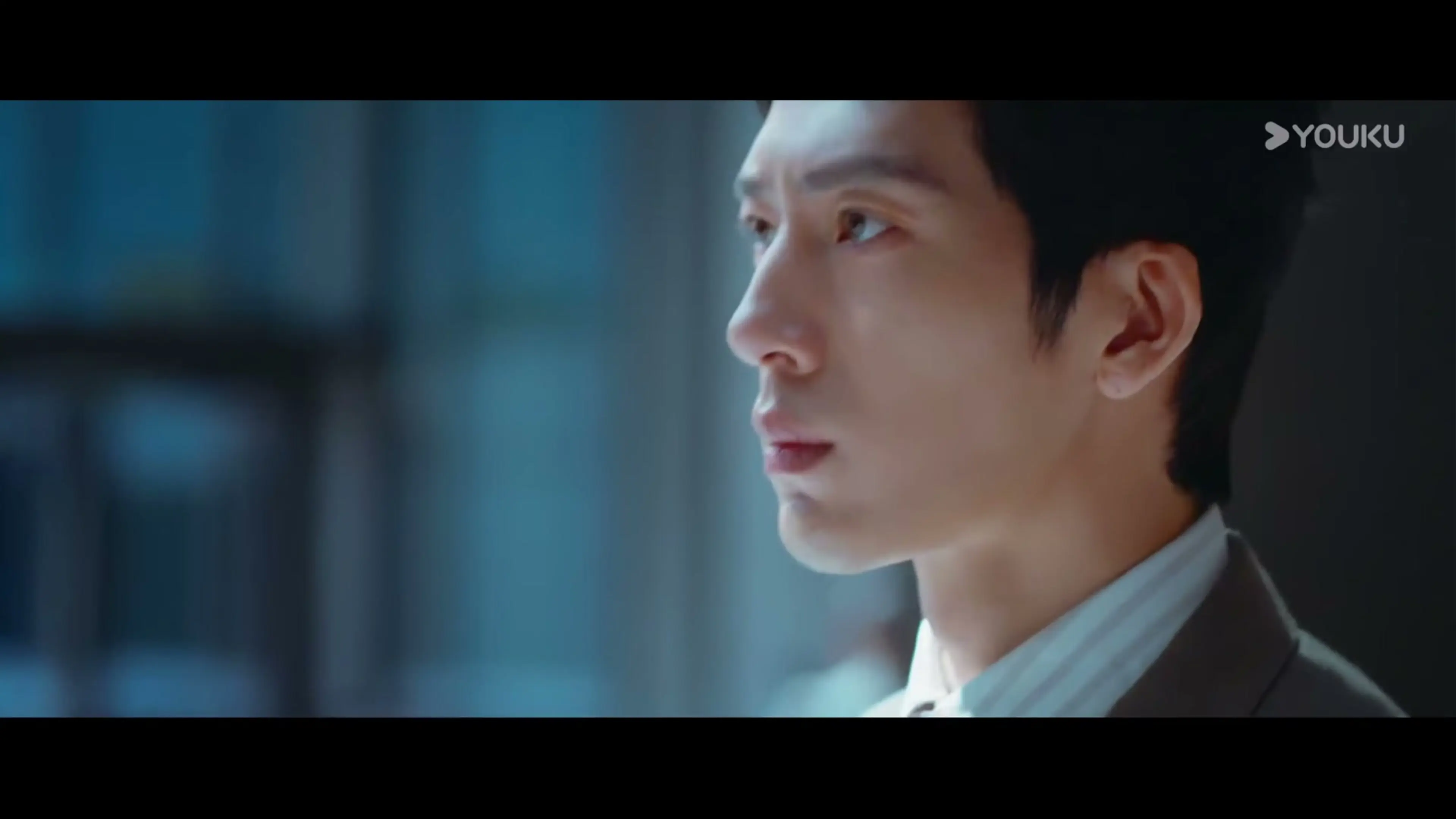 Jing Boran looks to the side in an office, wearing a dark jacket and pale shirt.