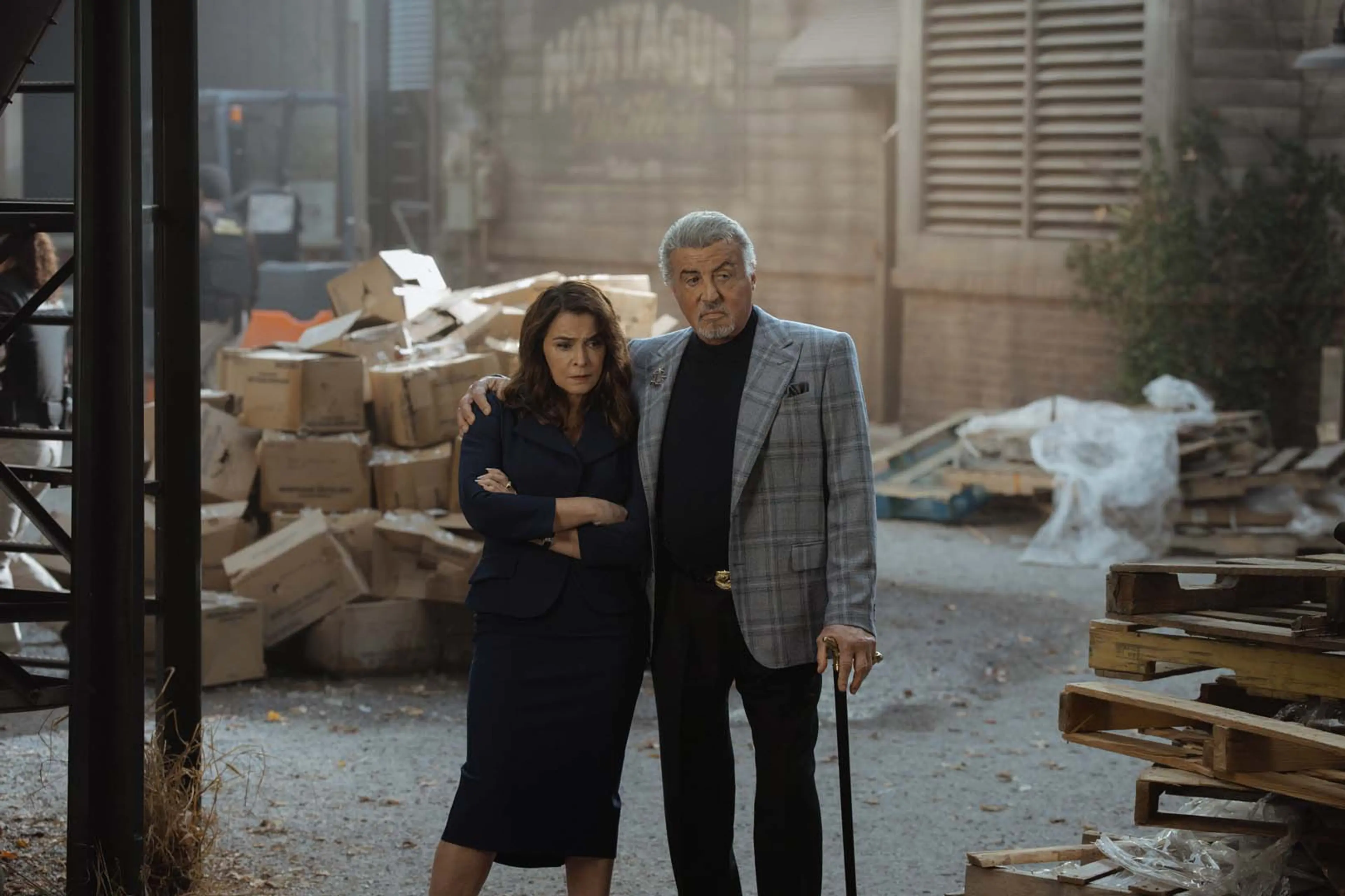 Annabella Sciorra as Joanne stands beside Sylvester Stallone as Dwight in a damaged loading area.