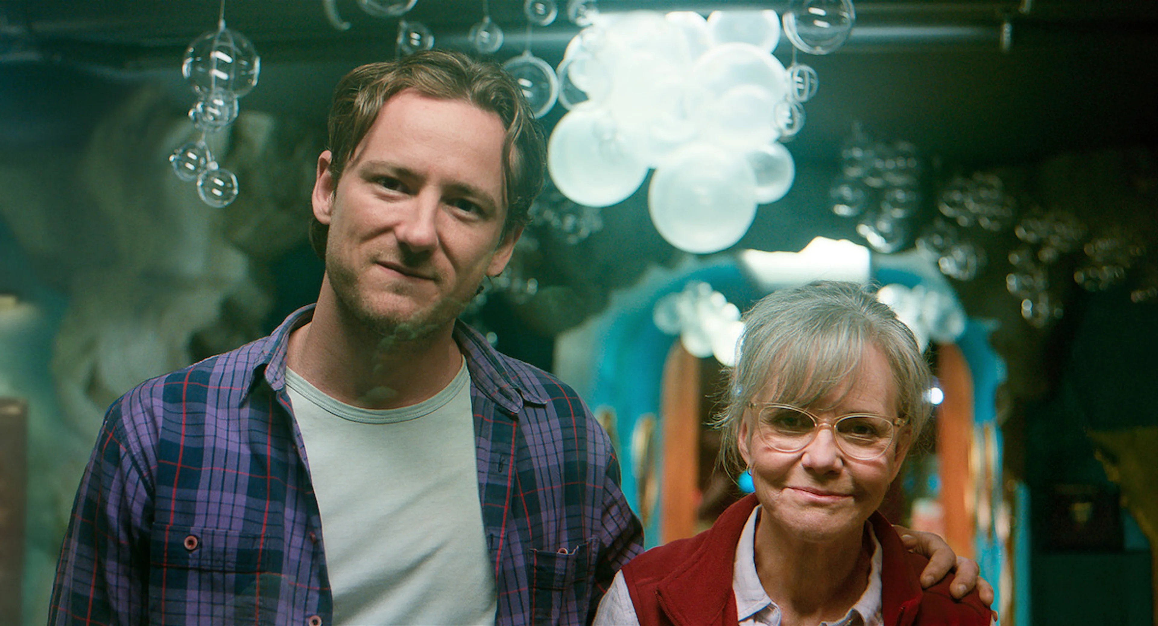 Lewis Pullman as Cameron stands beside Sally Field as Tova at the aquarium.