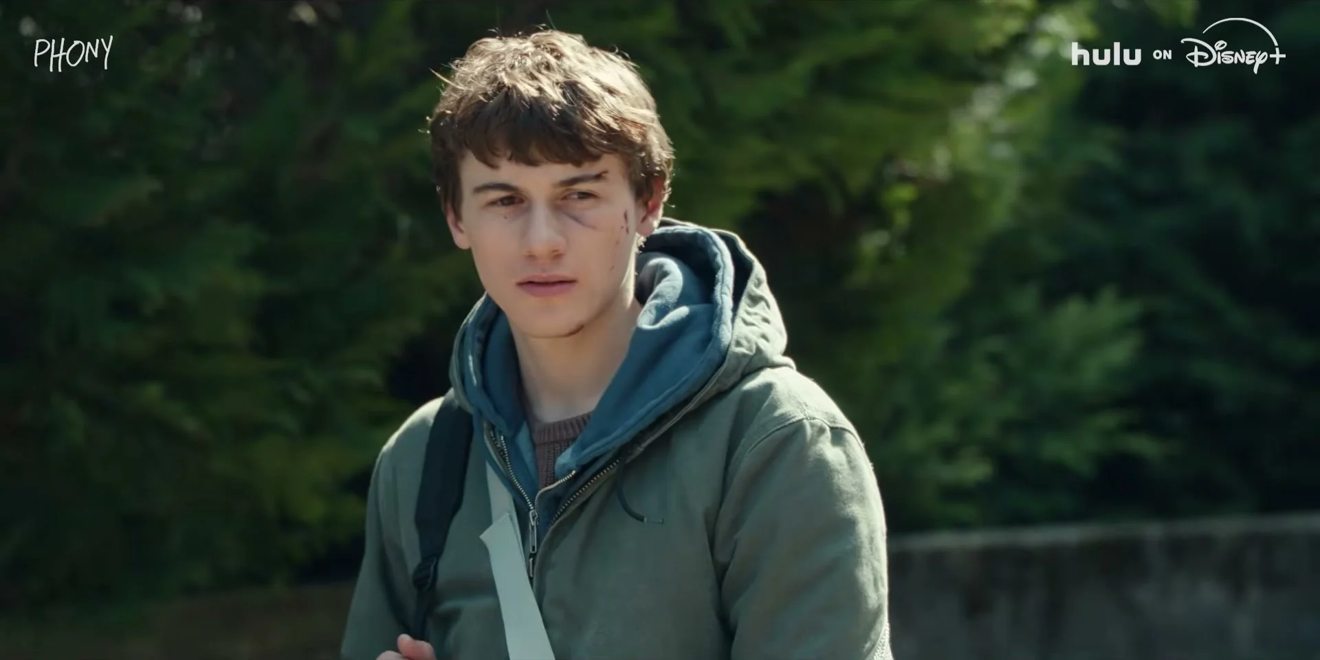 Sam Nivola stands outside in a hoodie in the Phony trailer.