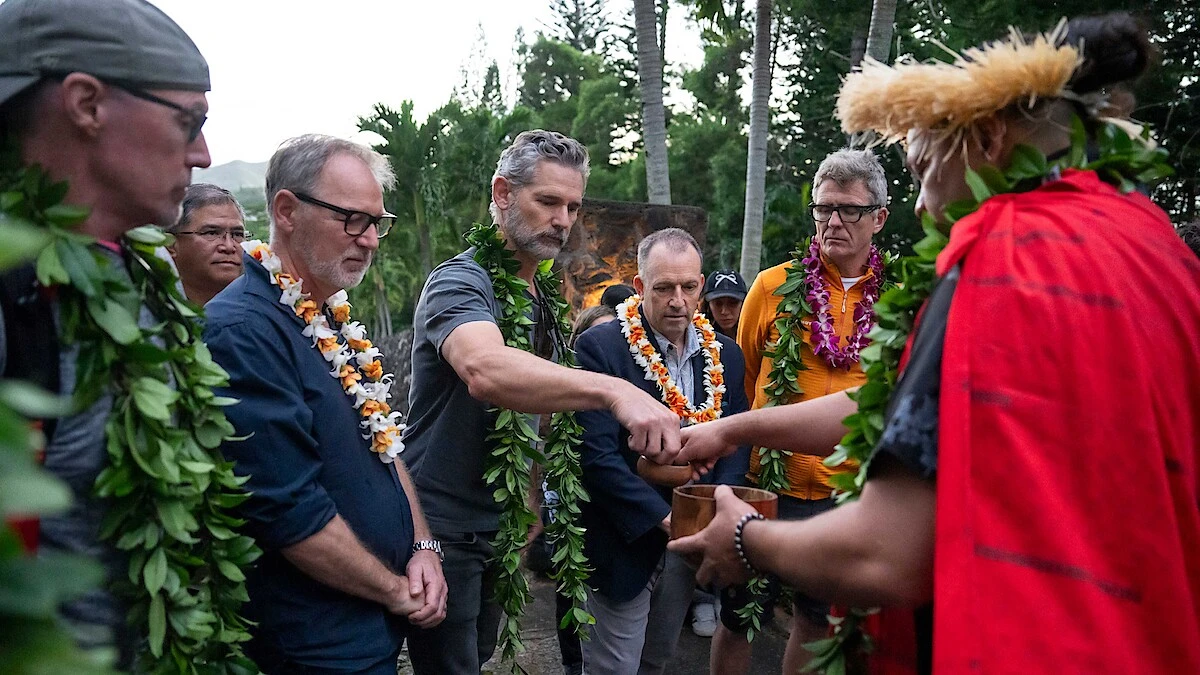 The UNTAMED Season 2 production team takes part in a Hawaiian blessing ceremony outdoors, with participants wearing leis.