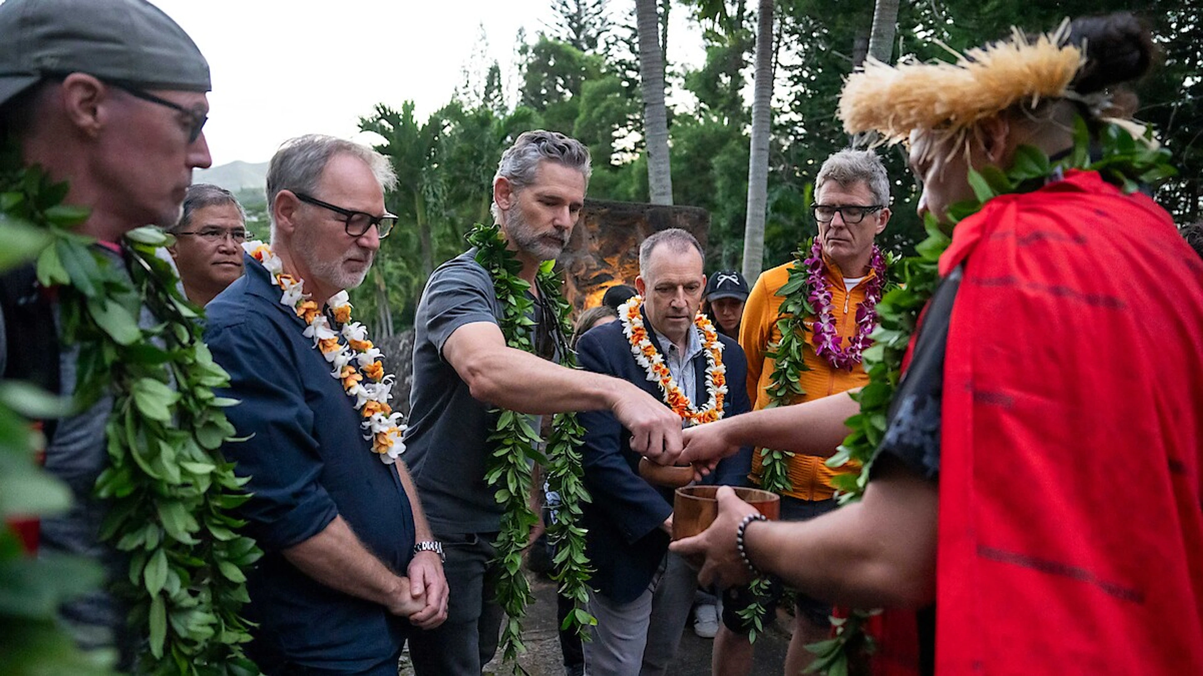 The UNTAMED Season 2 production team takes part in a Hawaiian blessing ceremony outdoors, with participants wearing leis.