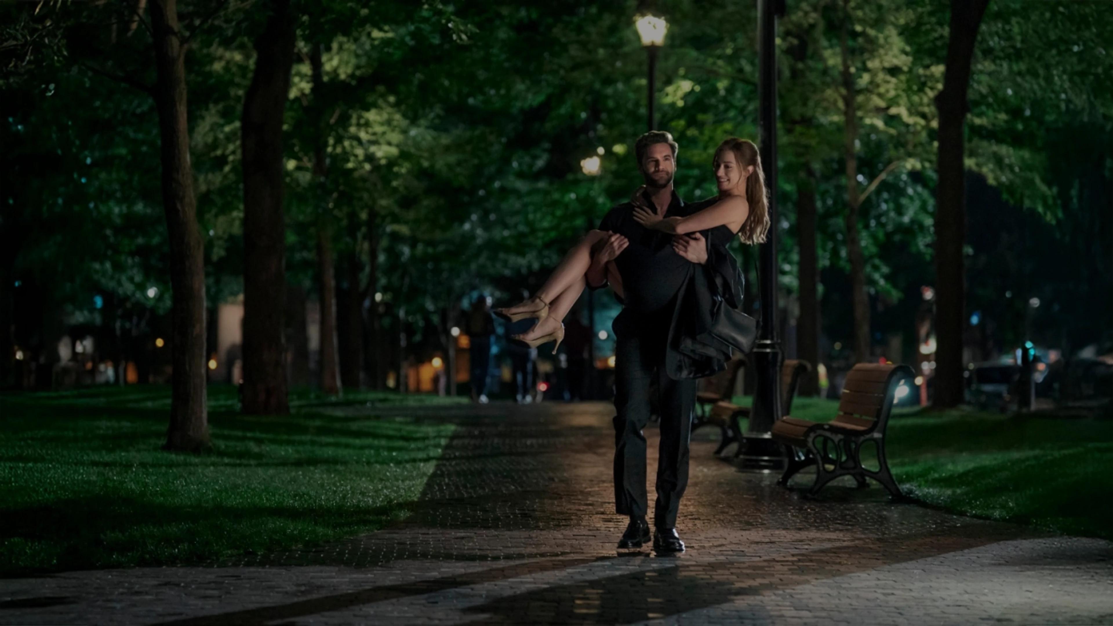 Adam Carlsen carries Olive Smith through a park at night in The Love Hypothesis.