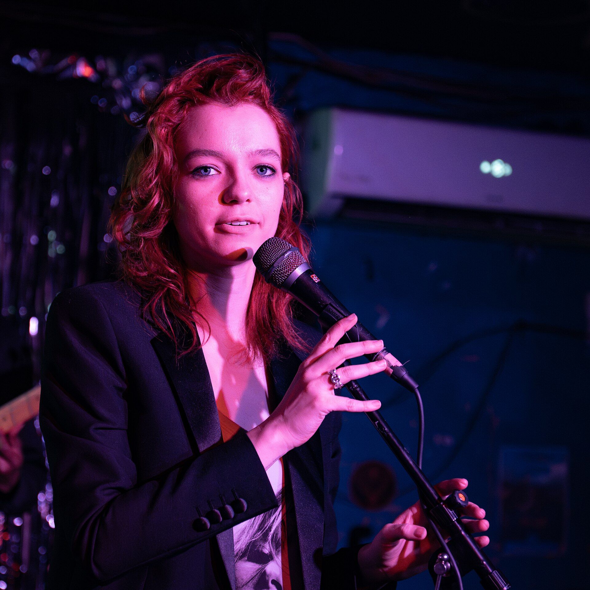 Esmé Creed-Miles speaking into a microphone at an event.