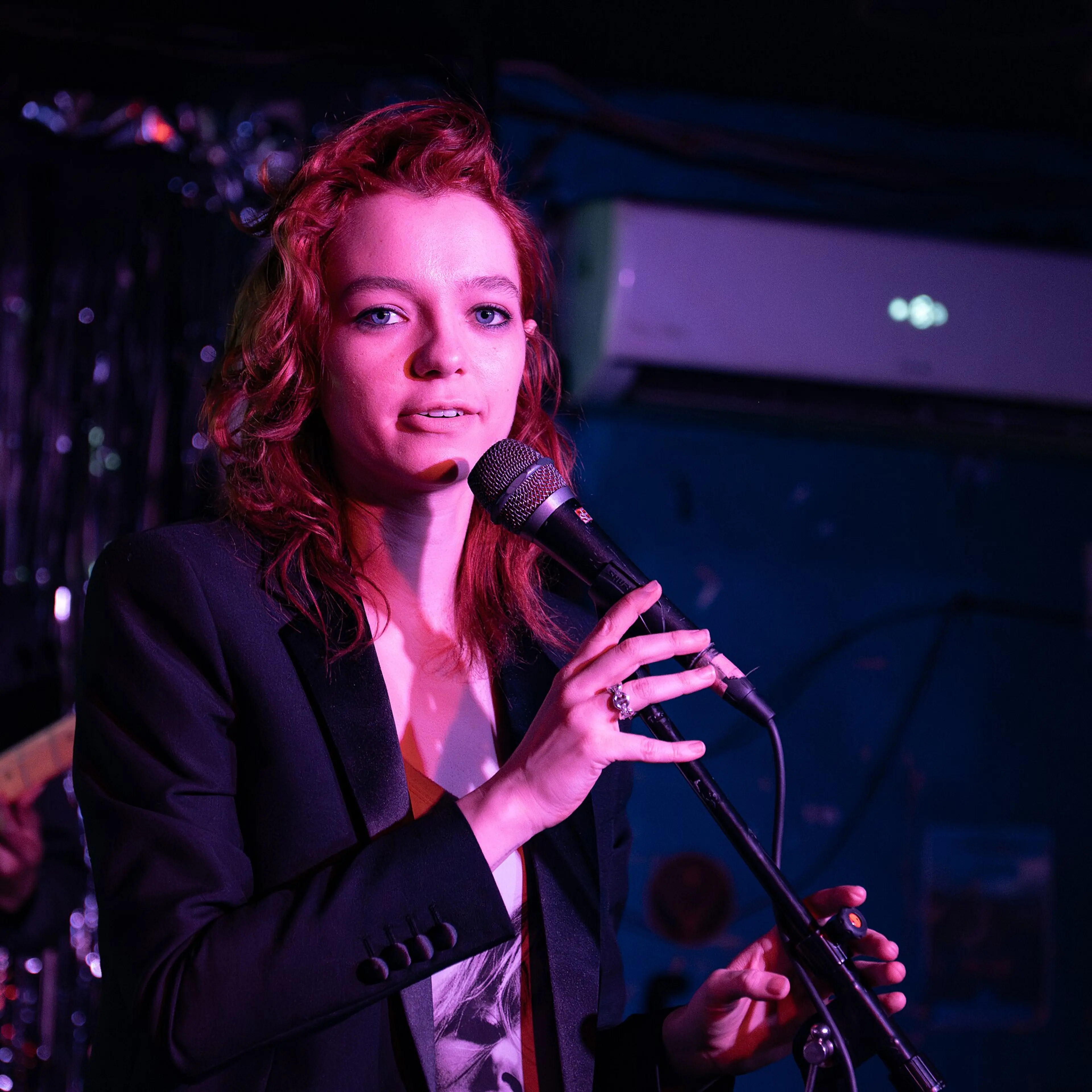 Esmé Creed-Miles speaking into a microphone at an event.