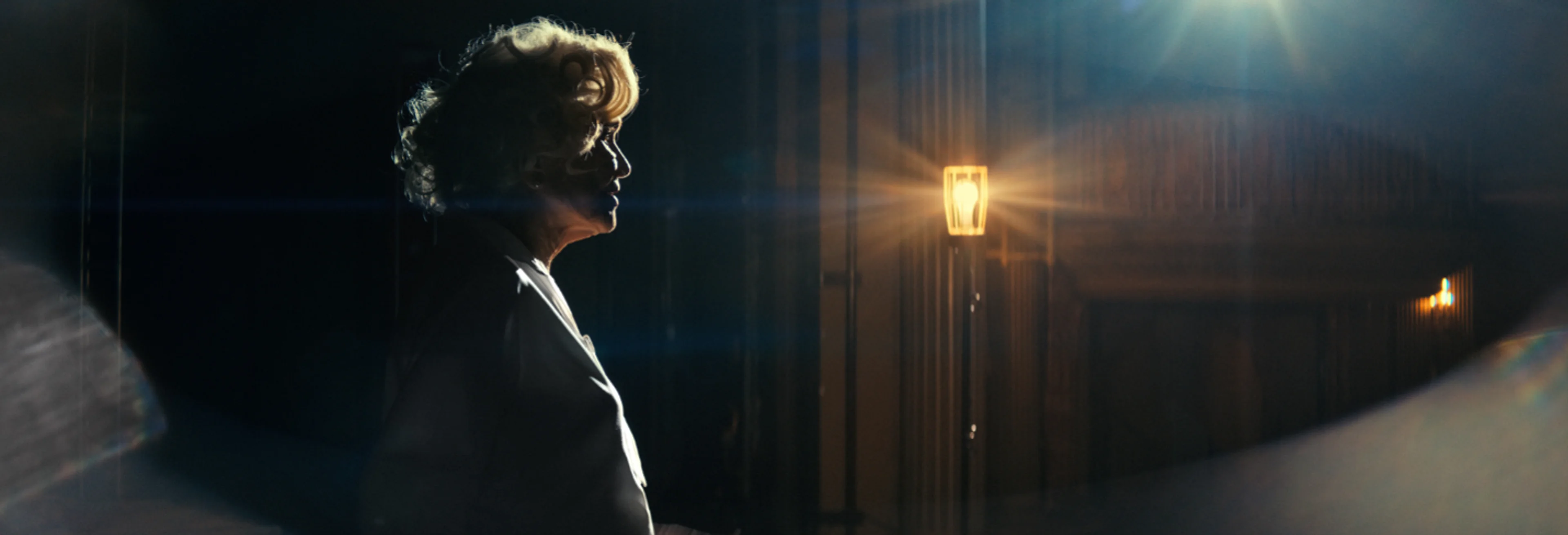 Ellen Burstyn as an imagined older Marilyn Monroe, standing in profile under theater lights in Flesh Impact.