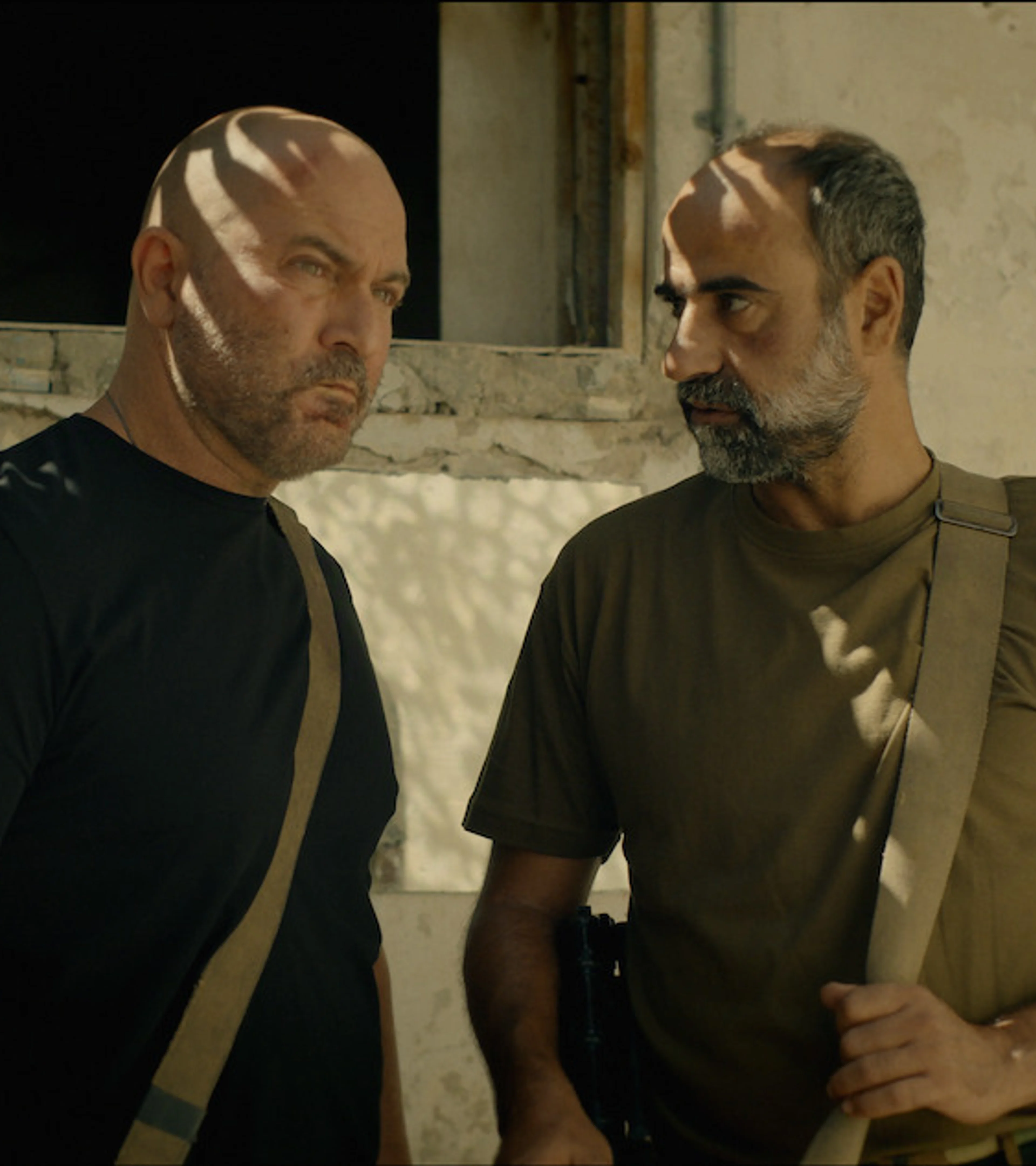 Doron and Eli stand inside a worn building in Fauda Season 5.