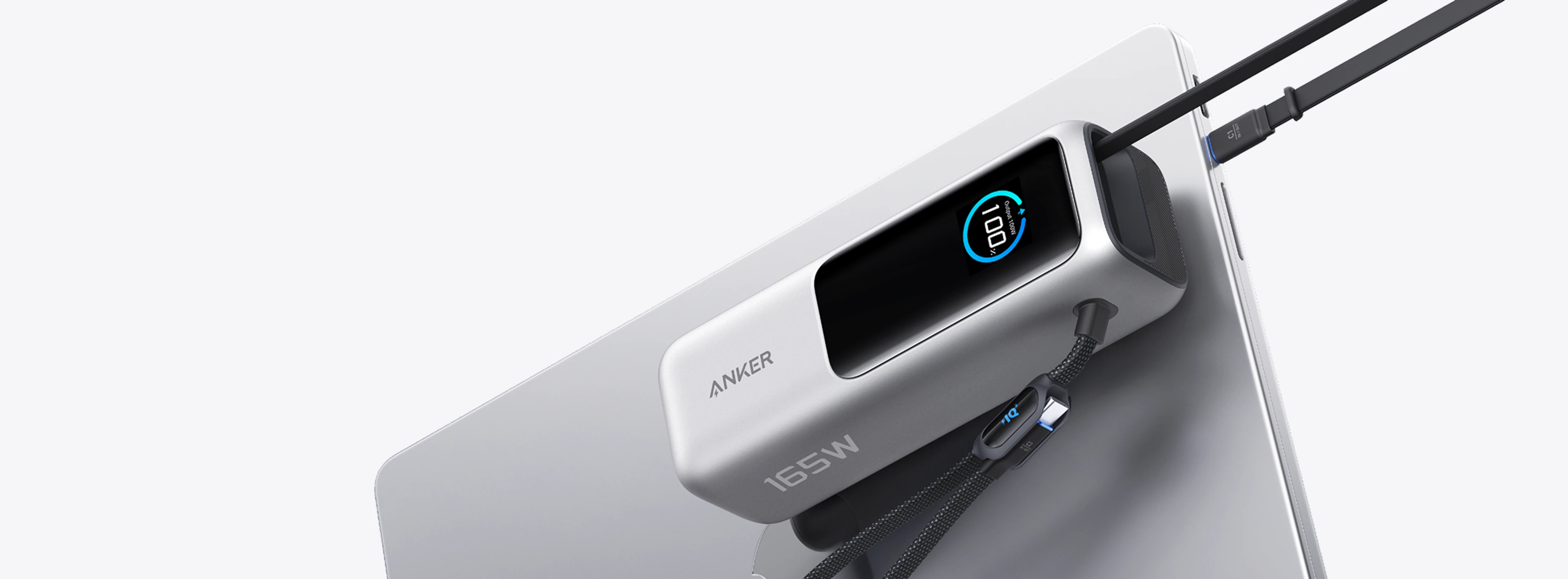 Silver Anker A1695 power bank beside a laptop with its integrated USB-C cables