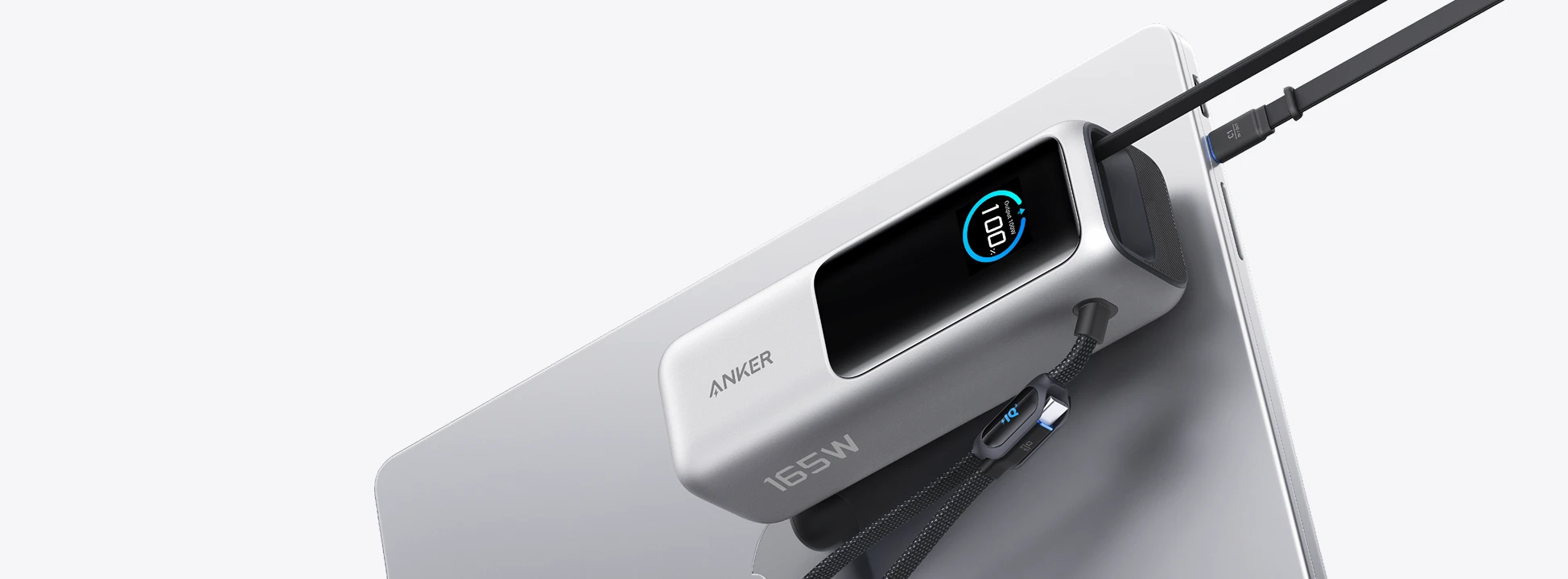 Silver Anker A1695 power bank beside a laptop with its integrated USB-C cables
