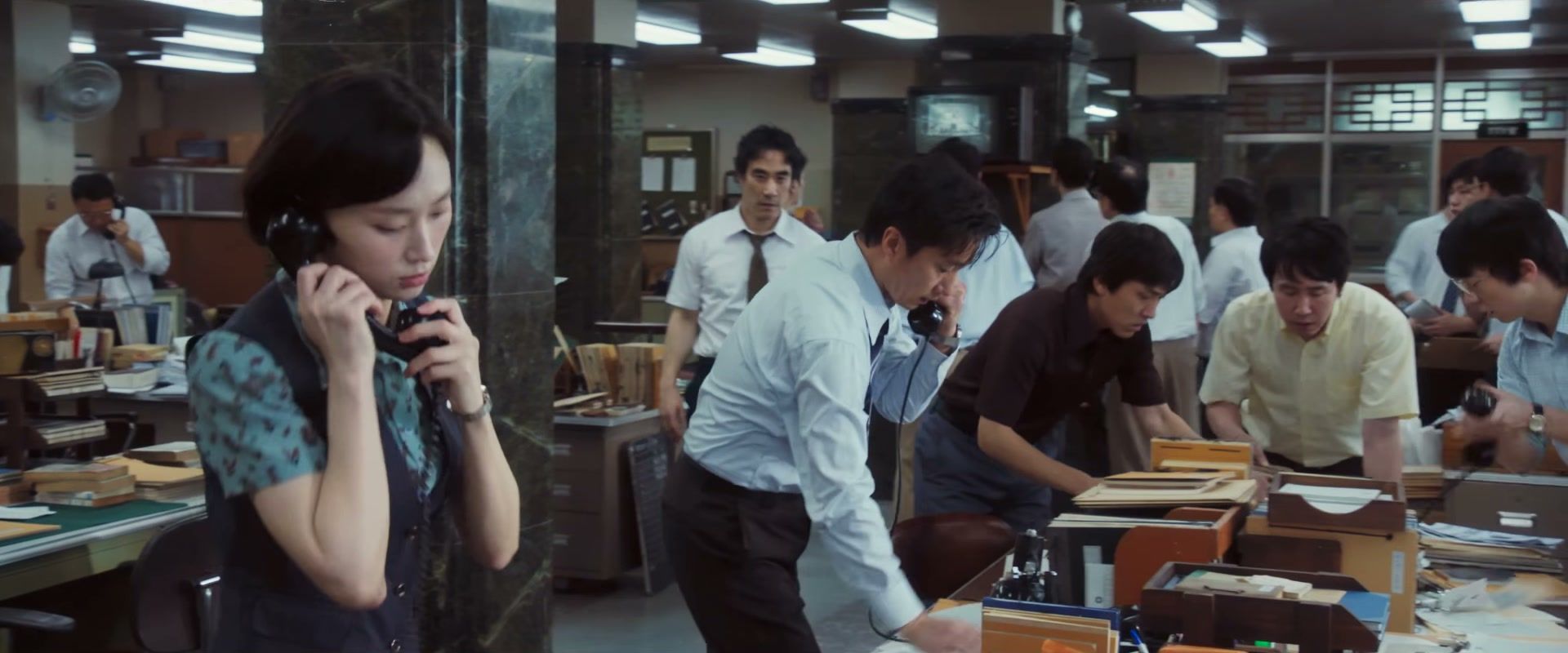Reporters work at phones and desks.