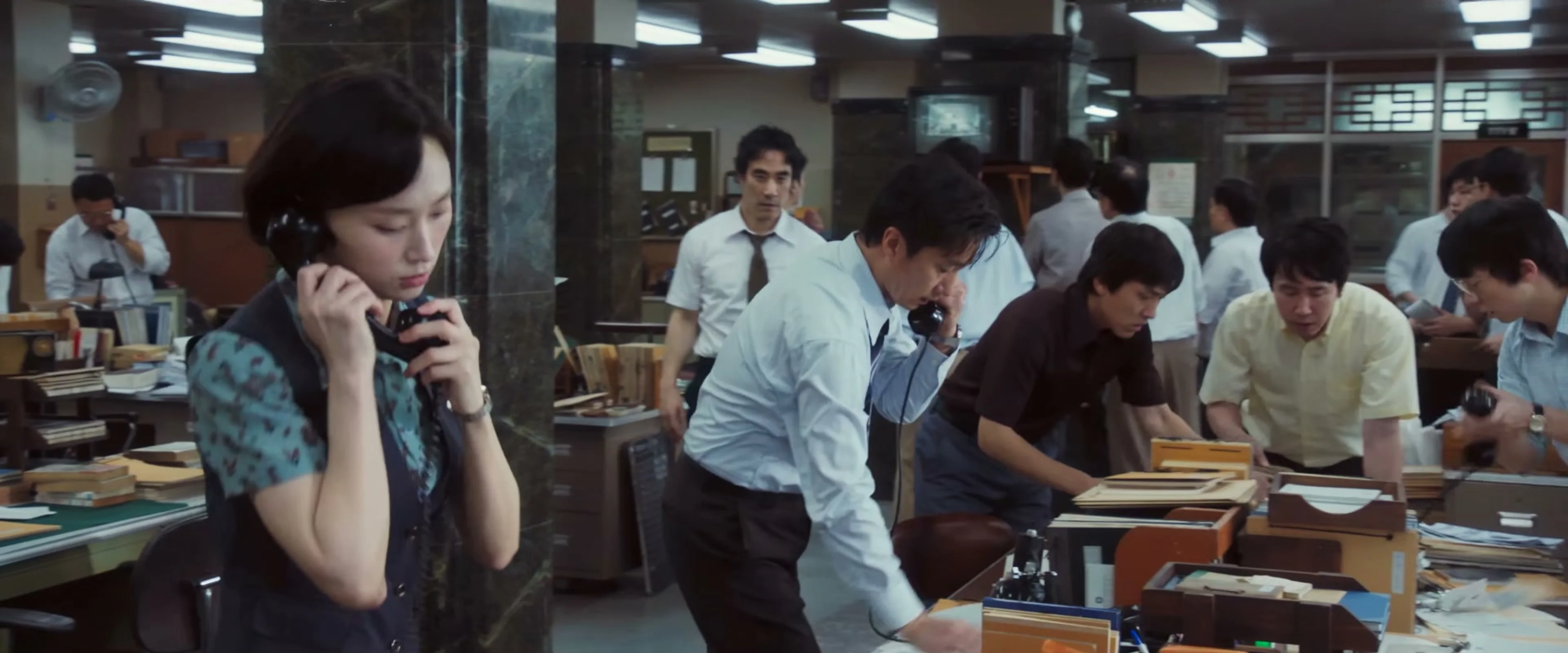 Reporters work at telephones and desks in the newsroom shown in The Assassin(s) trailer.