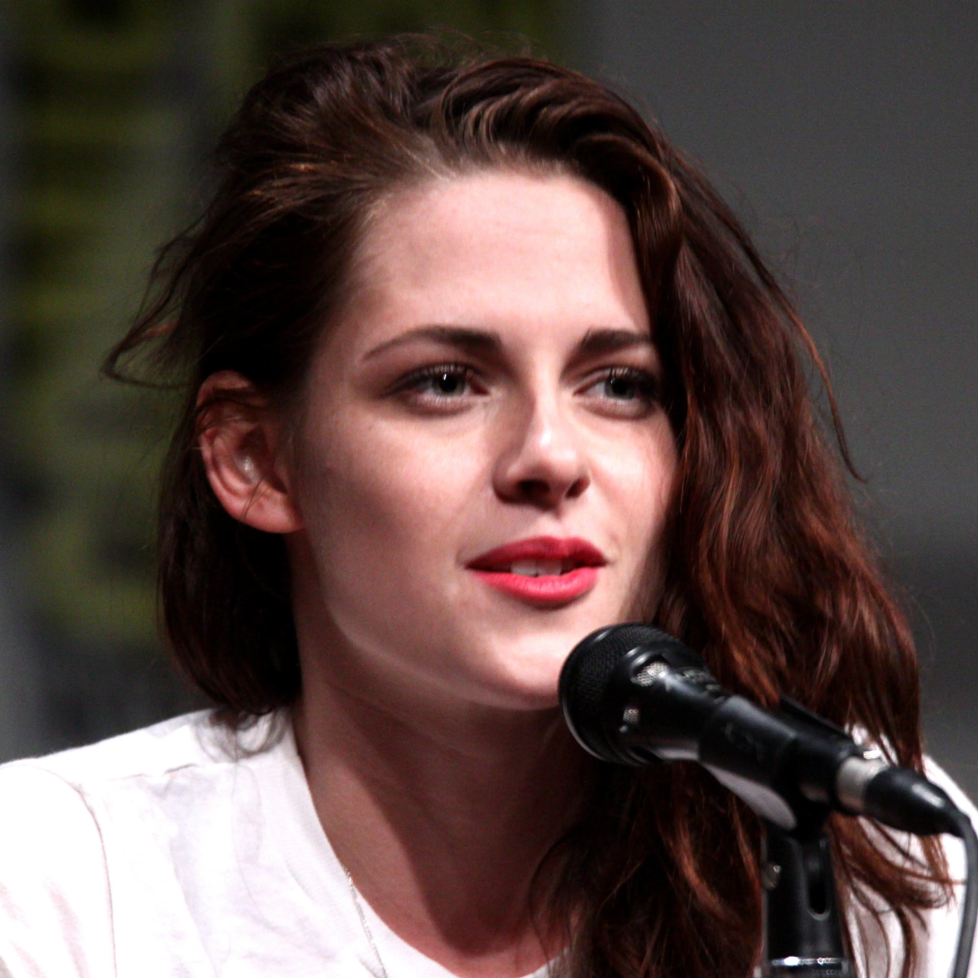Kristen Stewart speaking into a microphone at a 2012 Comic-Con panel.