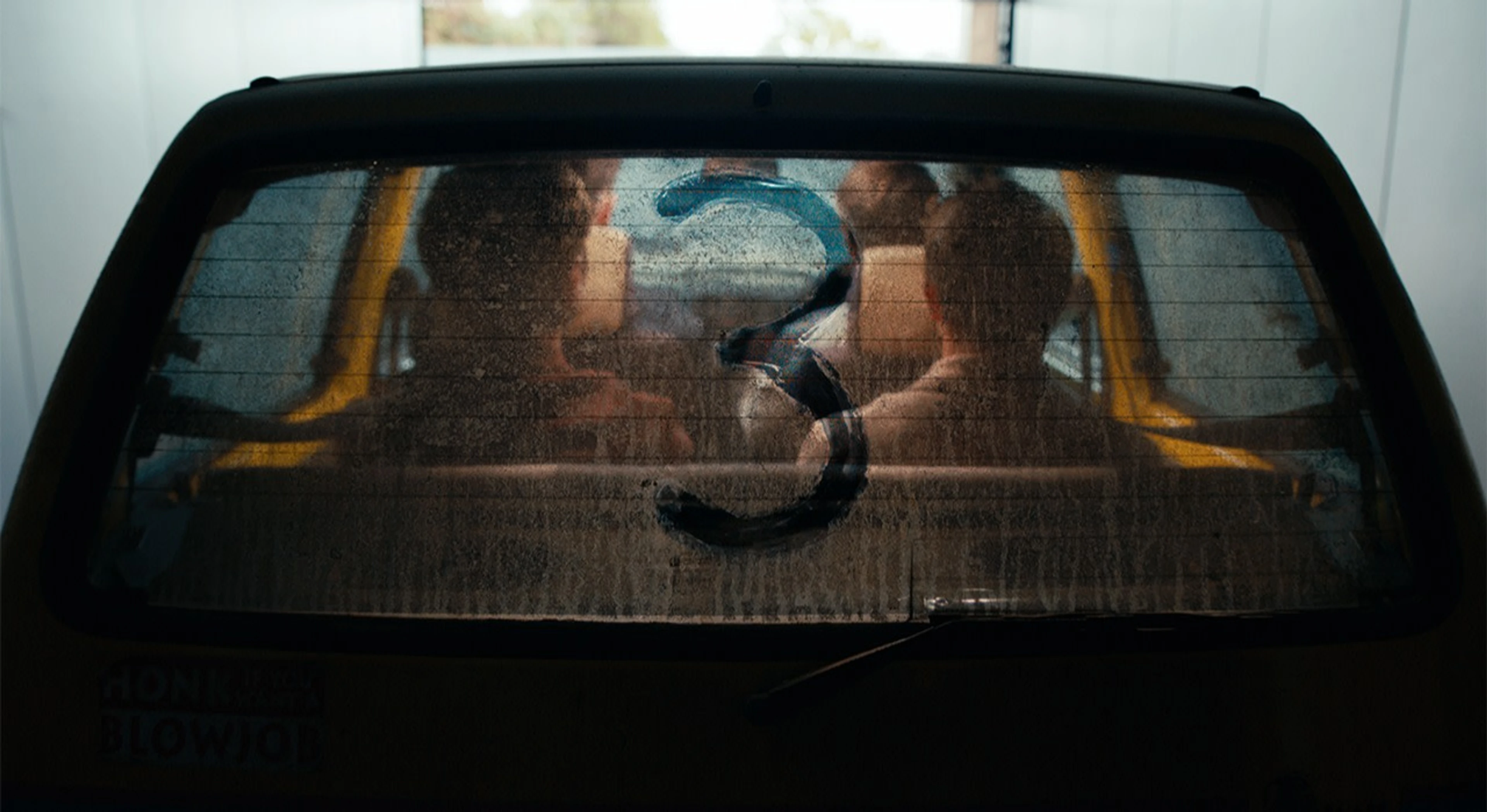 The returning Inbetweeners cast sit inside the yellow car behind a rear window marked with the number three.