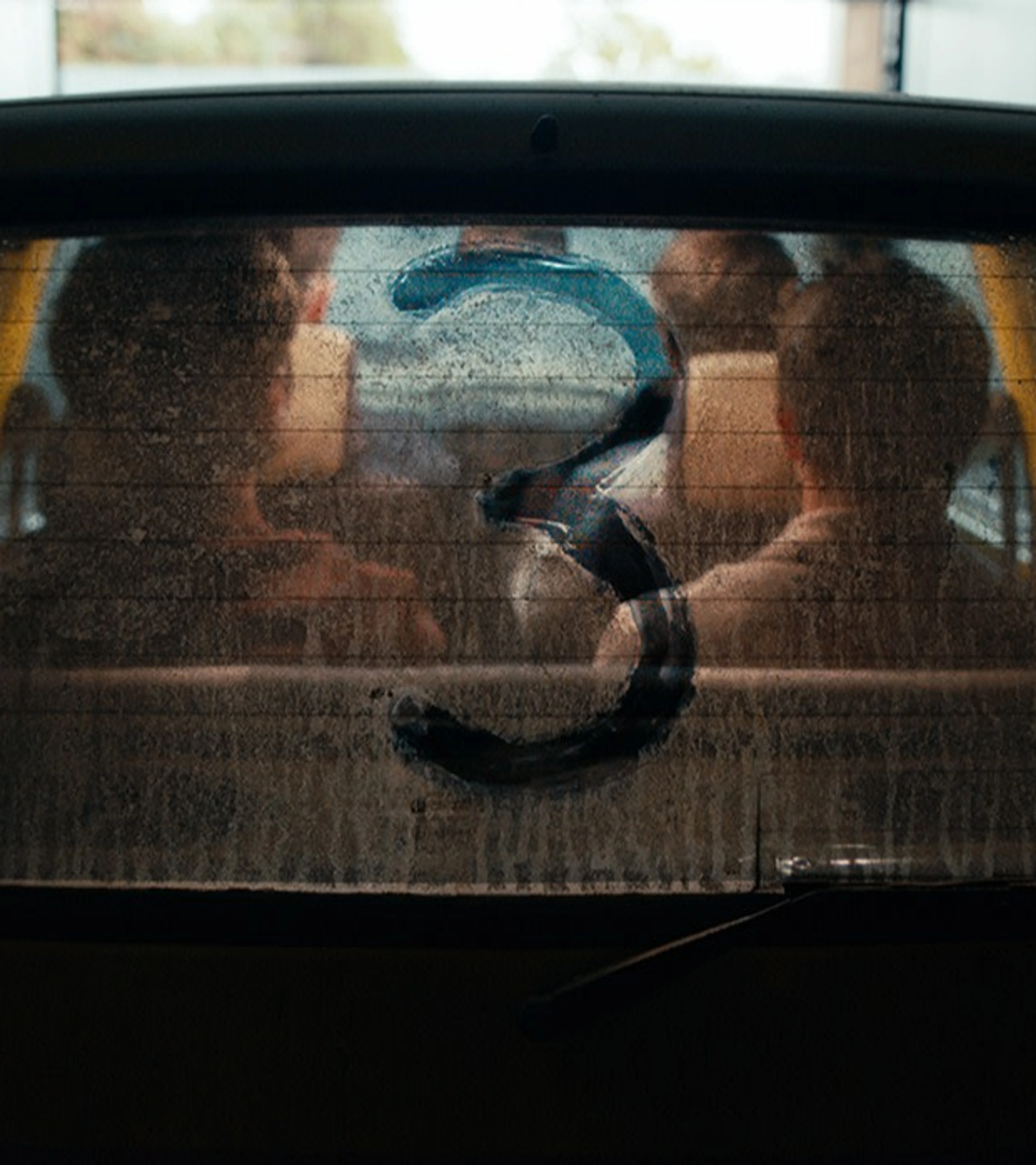 The returning Inbetweeners cast sit inside the yellow car behind a rear window marked with the number three.