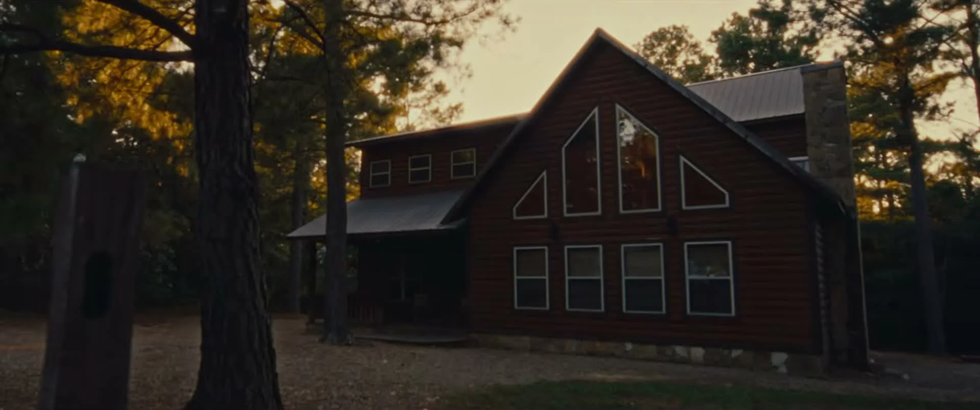 A dark wooden house stands among trees in the Marrow trailer.