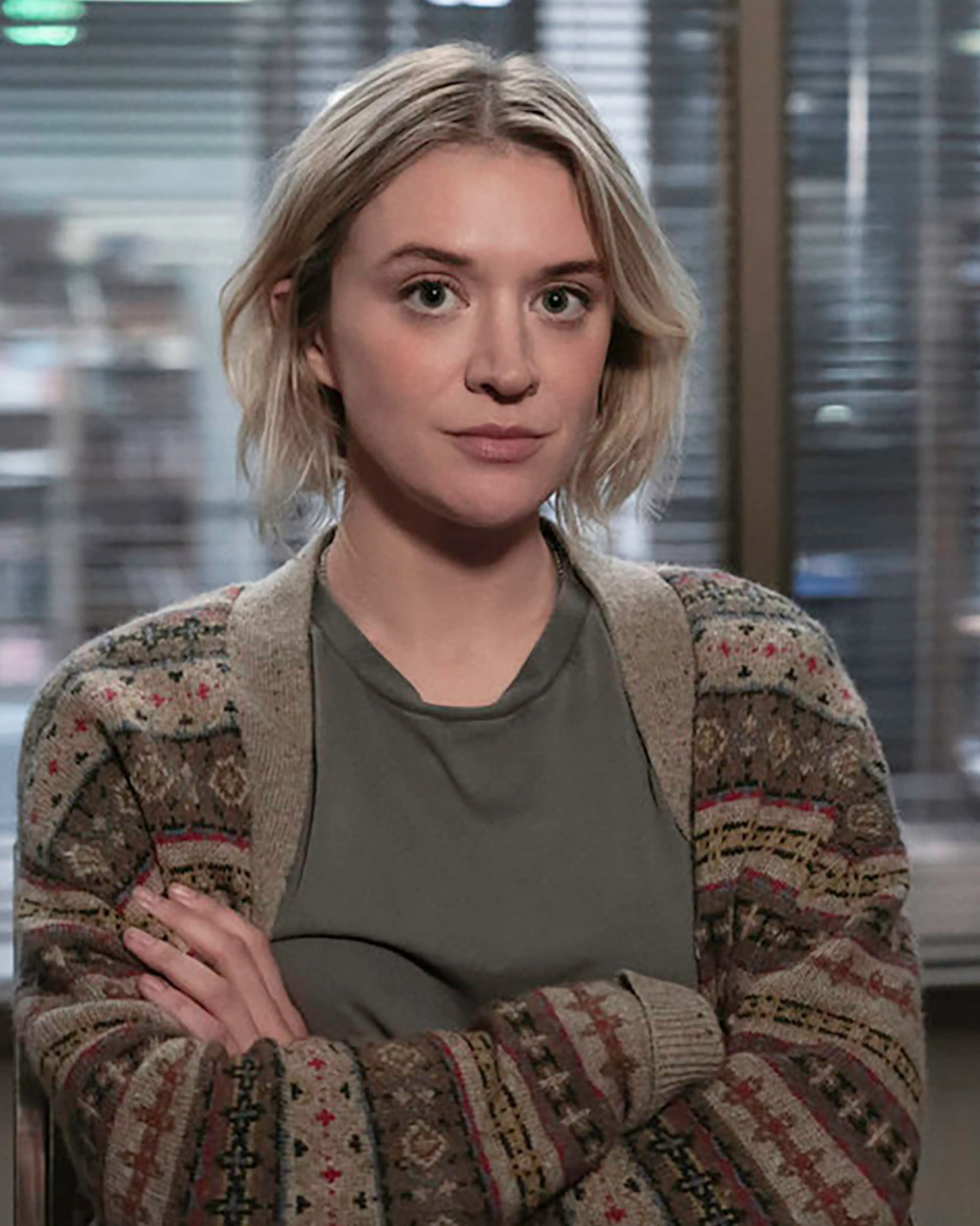 Mare sits in the newsroom wearing a brown jacket over a grey shirt.