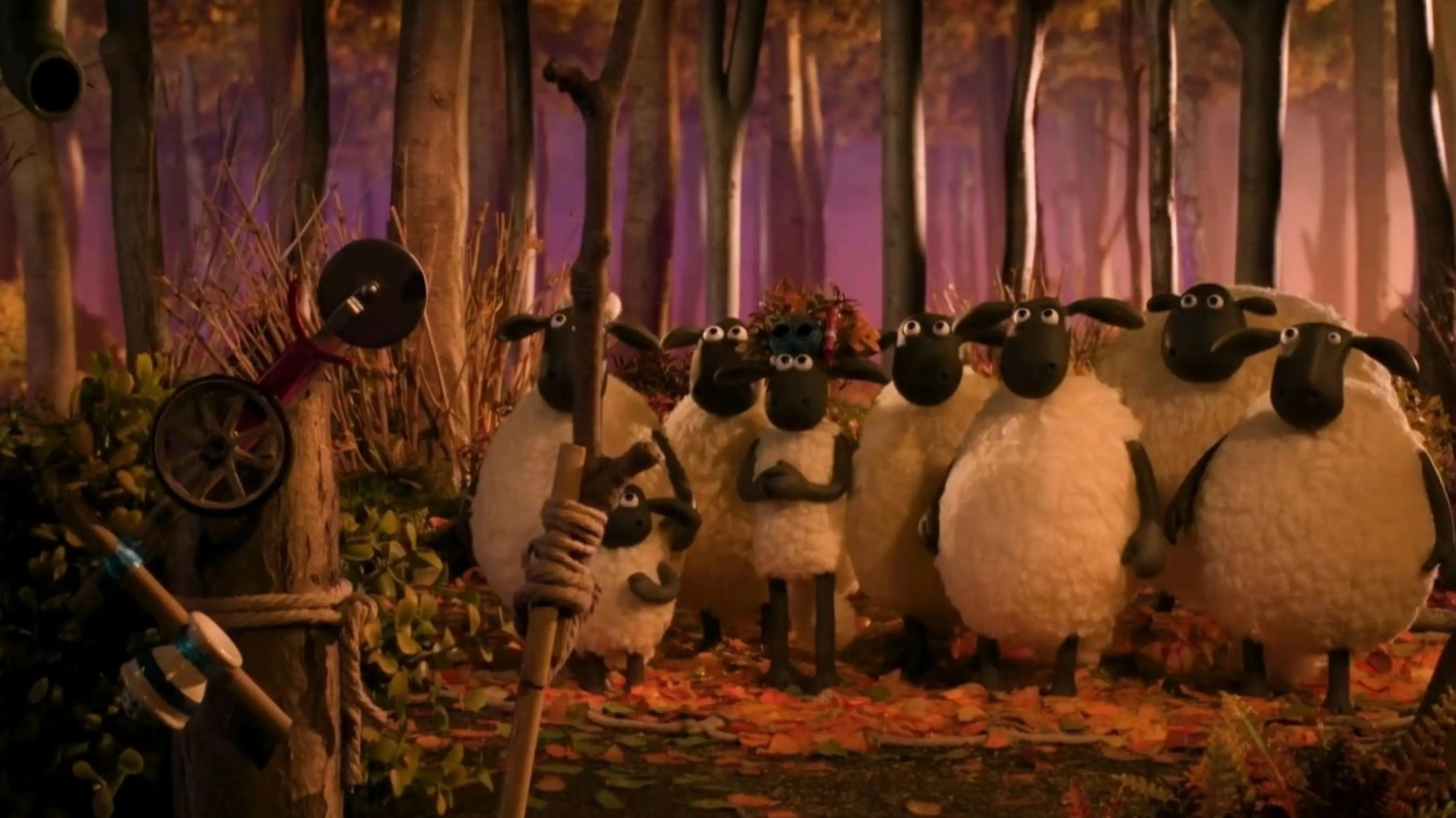 Shaun and the flock gather among trees and fallen autumn leaves.