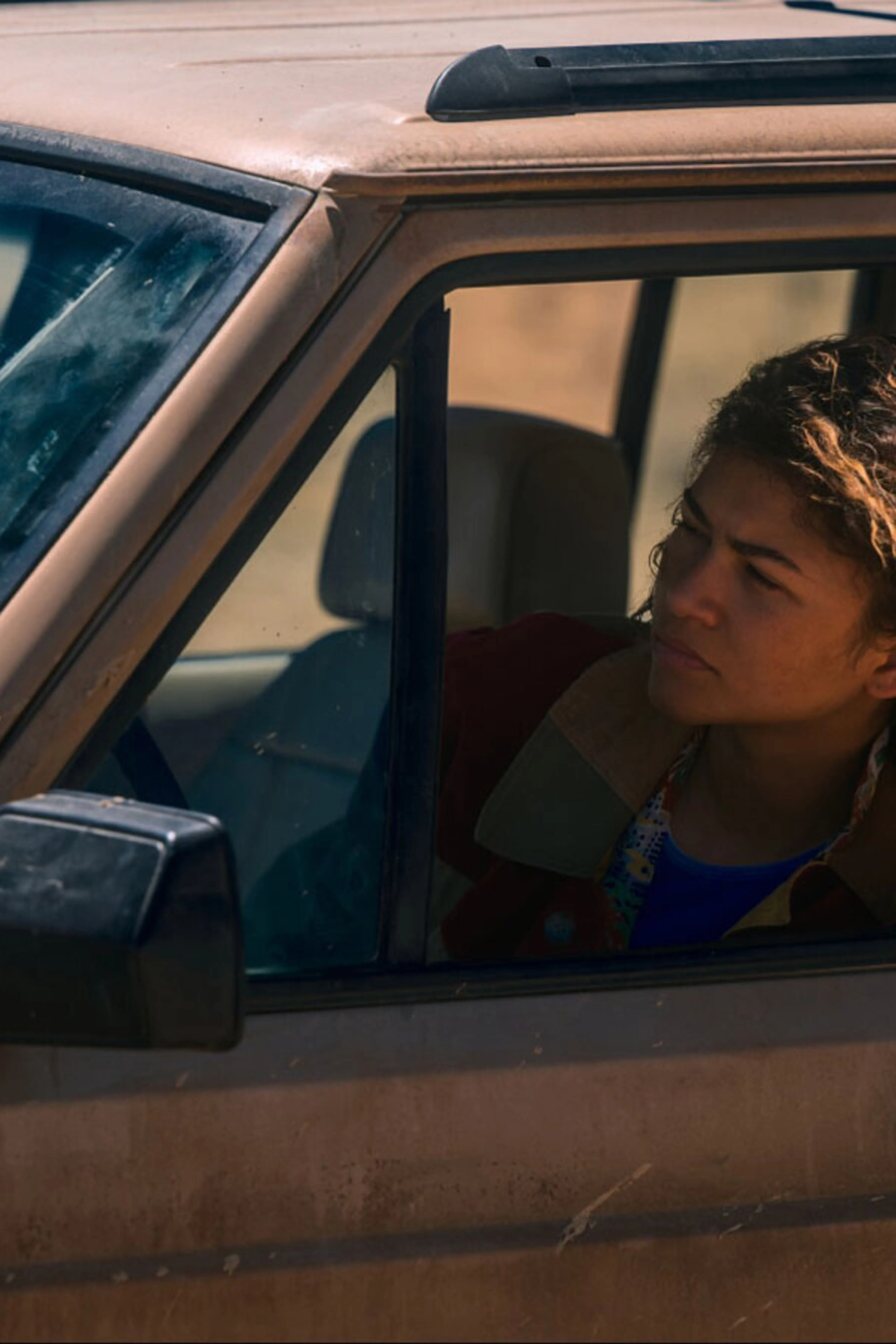 Zendaya as Rue looks from the window of a vehicle in an official HBO series still.