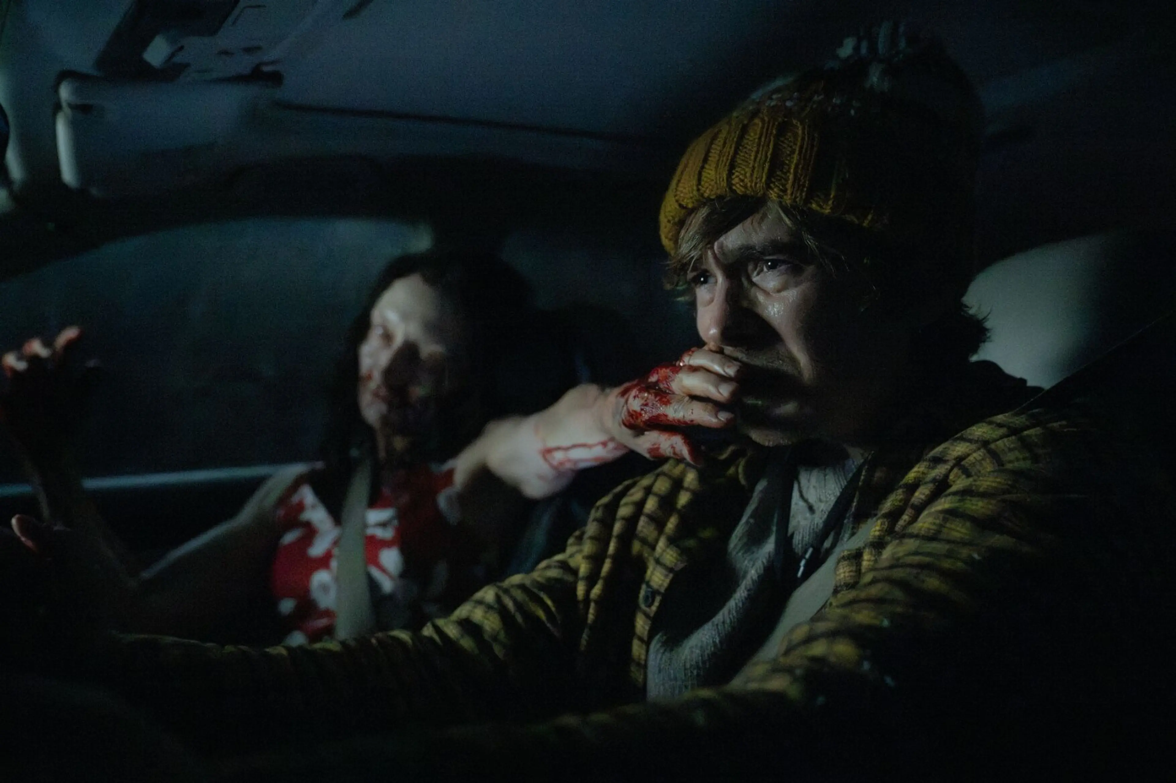 Austin Abrams as Bryan drives in a yellow knit cap beside an injured passenger.
