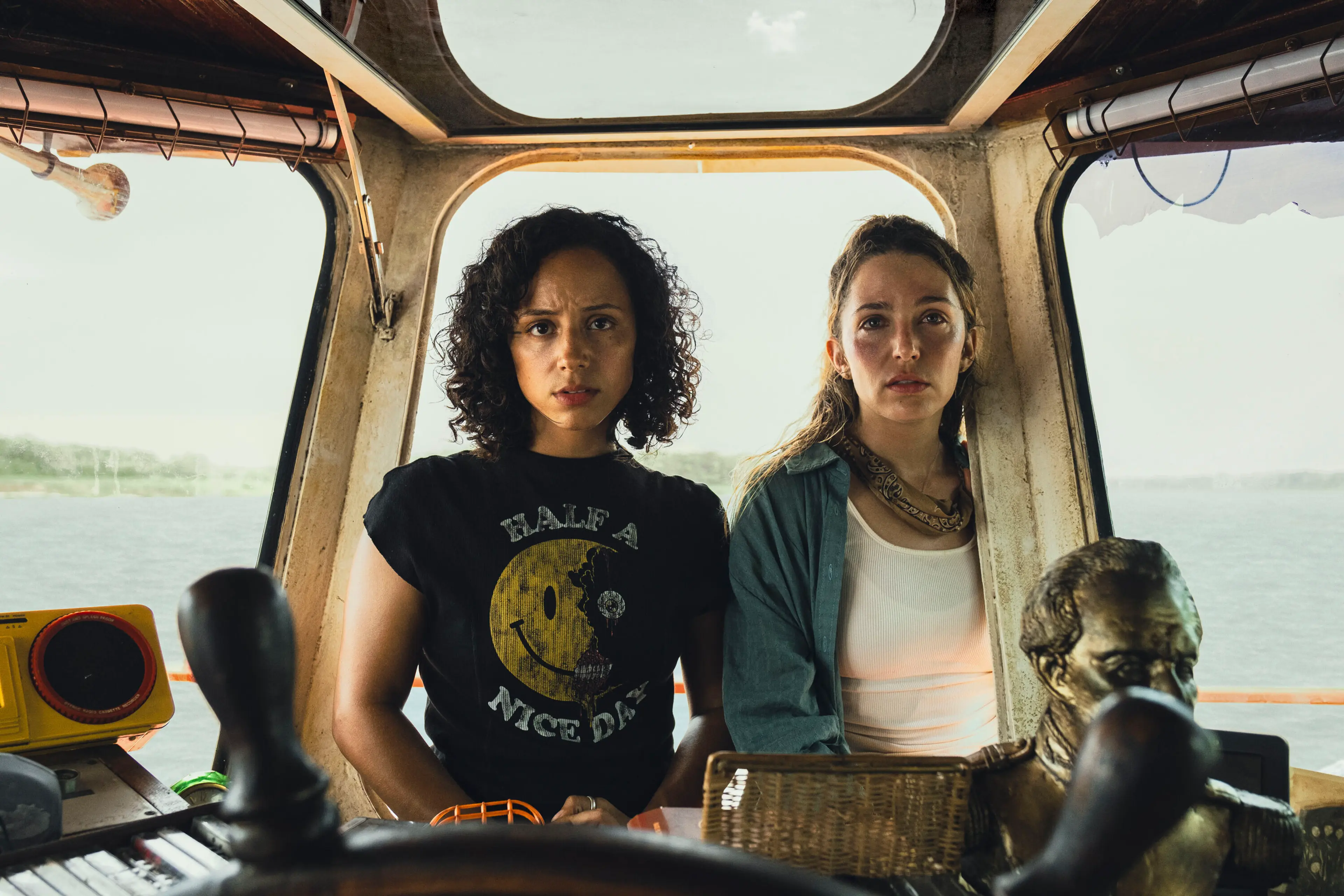 Kiana Madeira and Jessica Rothe stand at the controls of a river boat in Beware Boiúna.