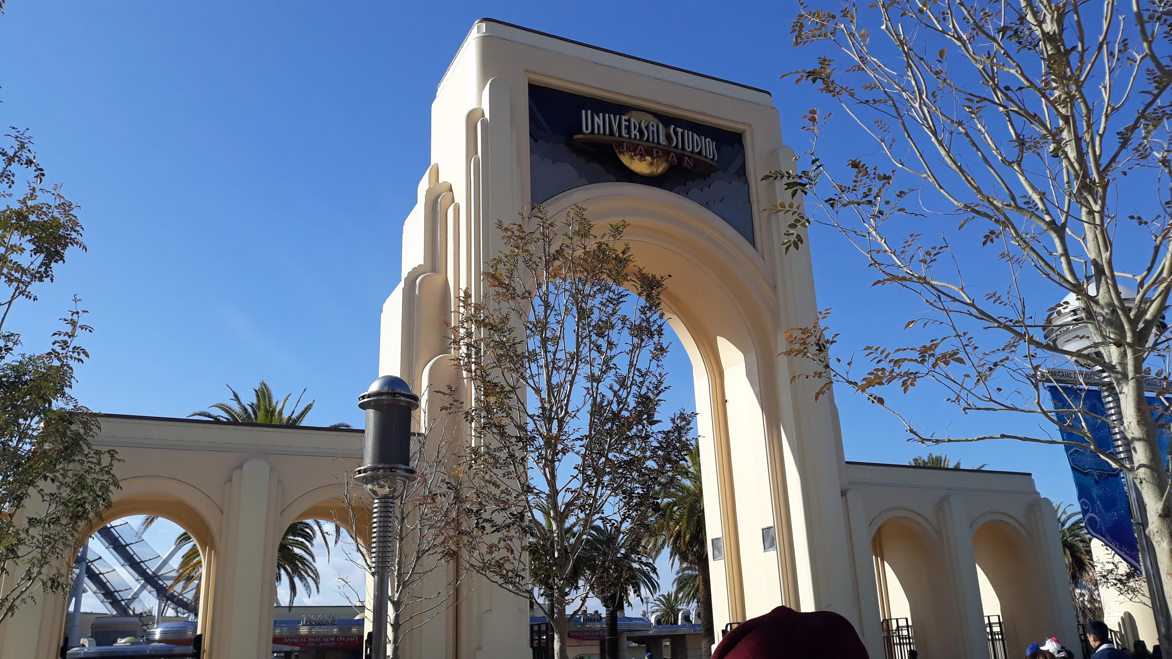 The cream-colored Universal Studios Japan entrance arch stands against a clear blue sky in Osaka.