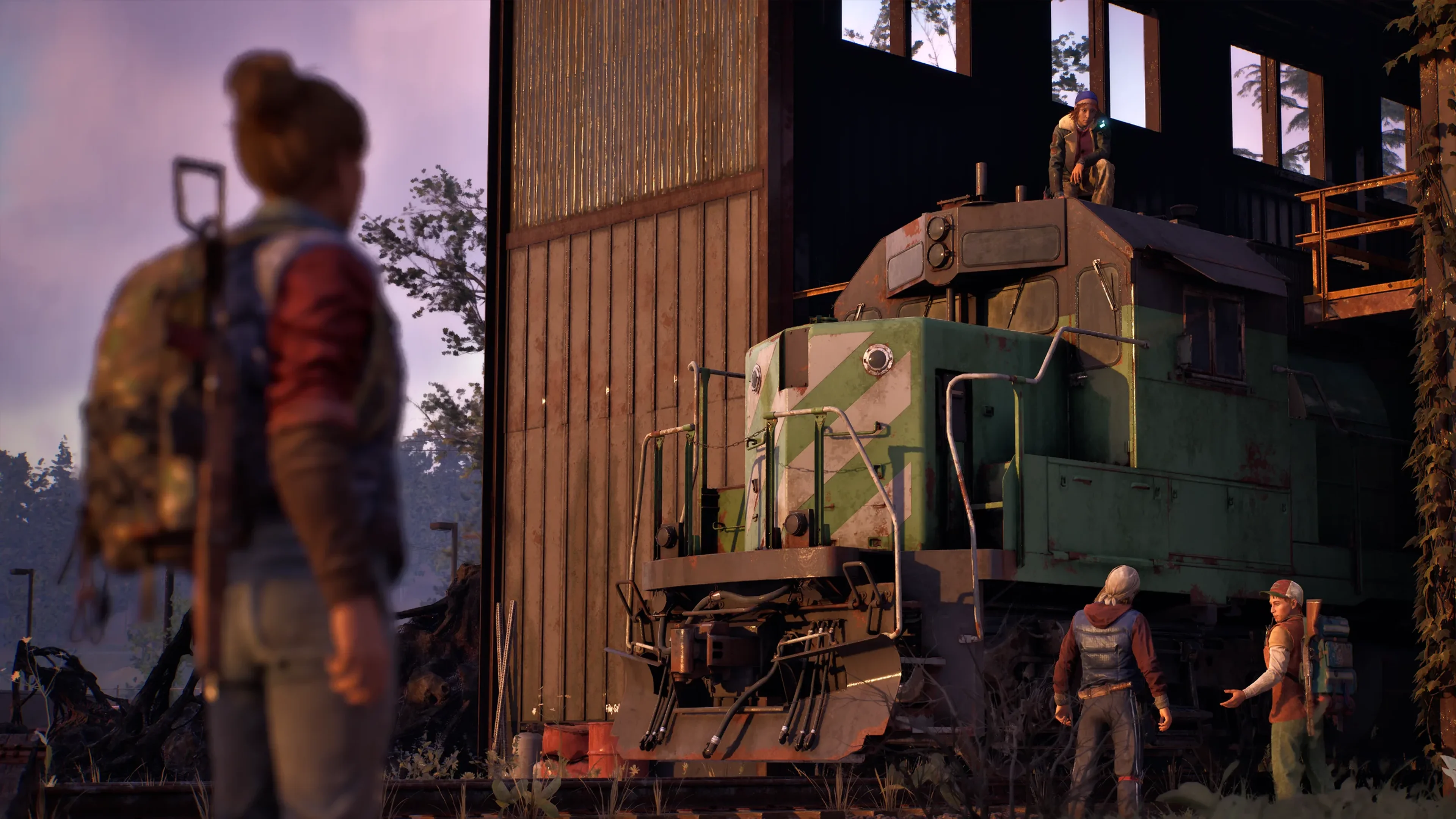 State of Decay 3 survivors gather around a green train engine inside a depot.