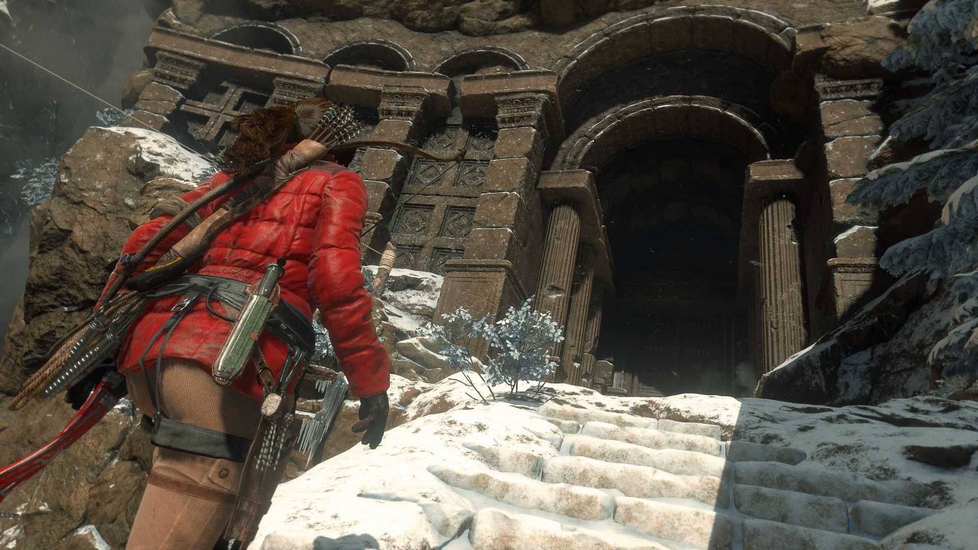 Lara approaches the stone doorway of a snow-covered ancient building.