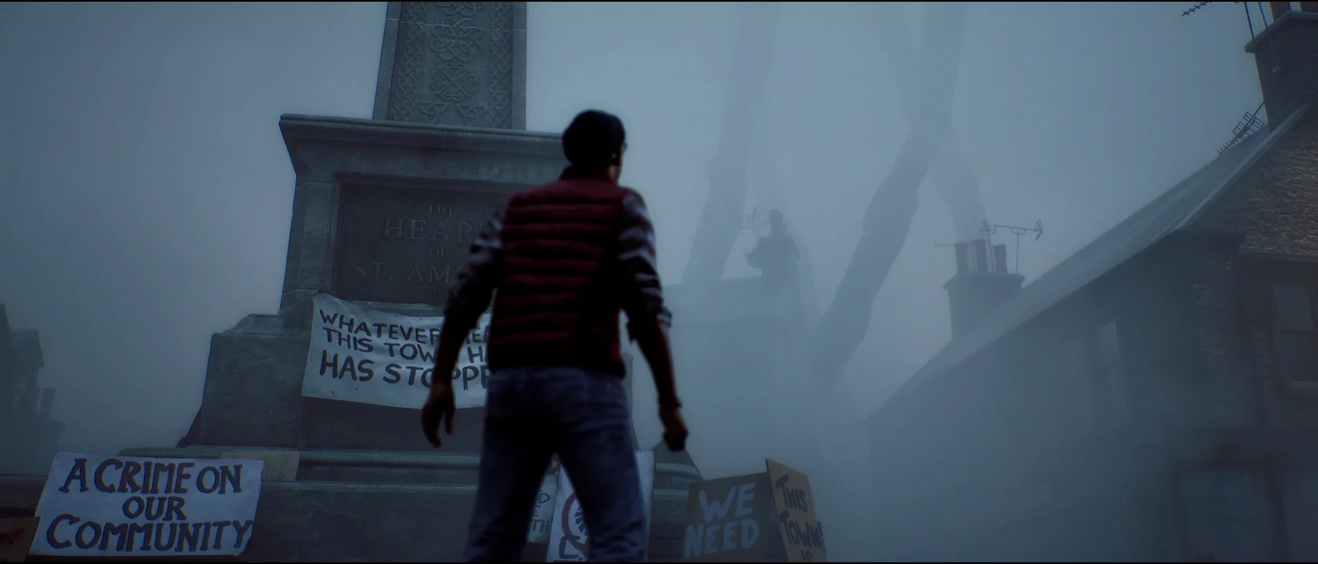 Simon stands near a town memorial surrounded by protest signs in a foggy square.
