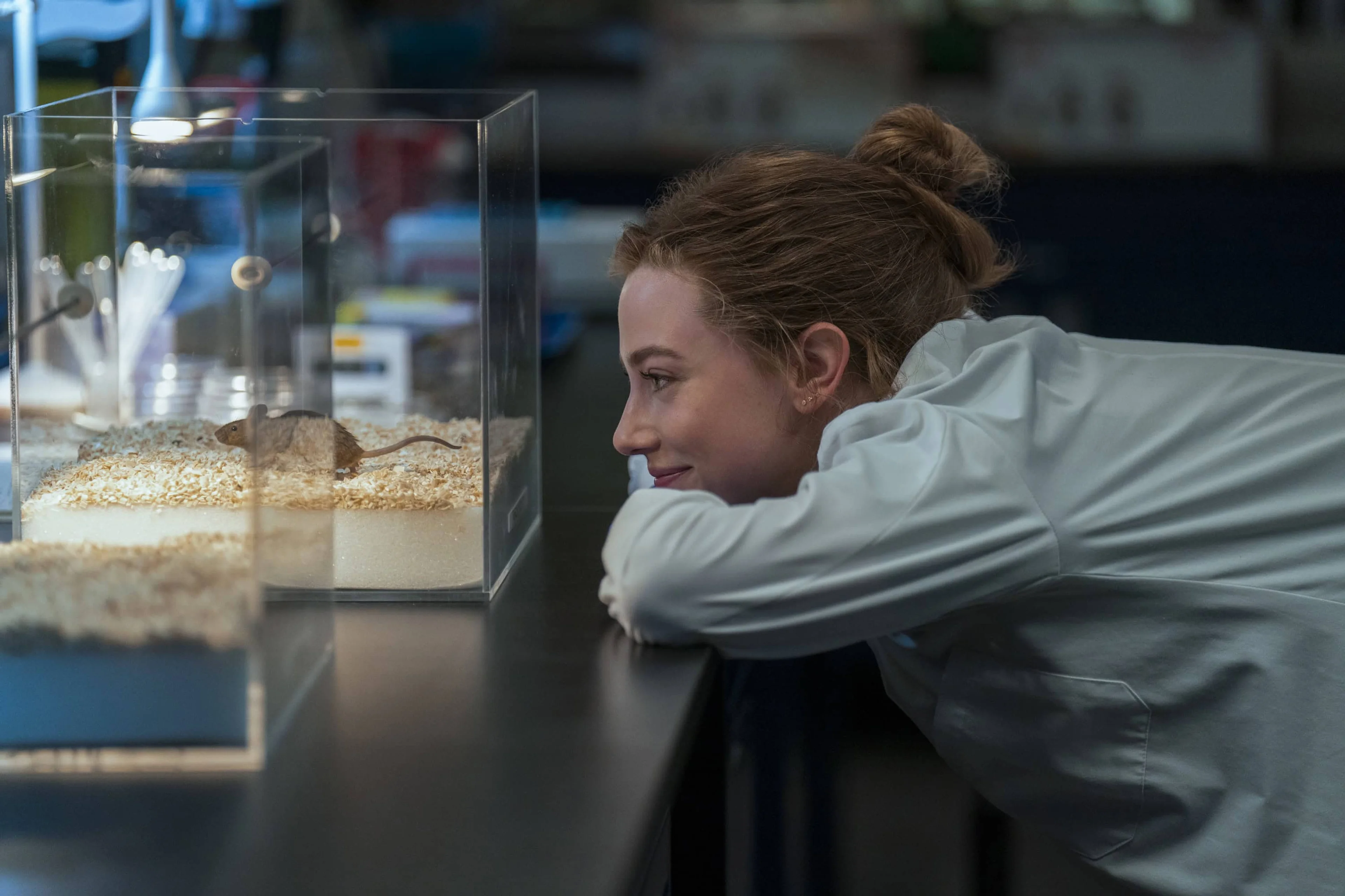 Olive rests her arms on a laboratory bench beside a mouse enclosure.