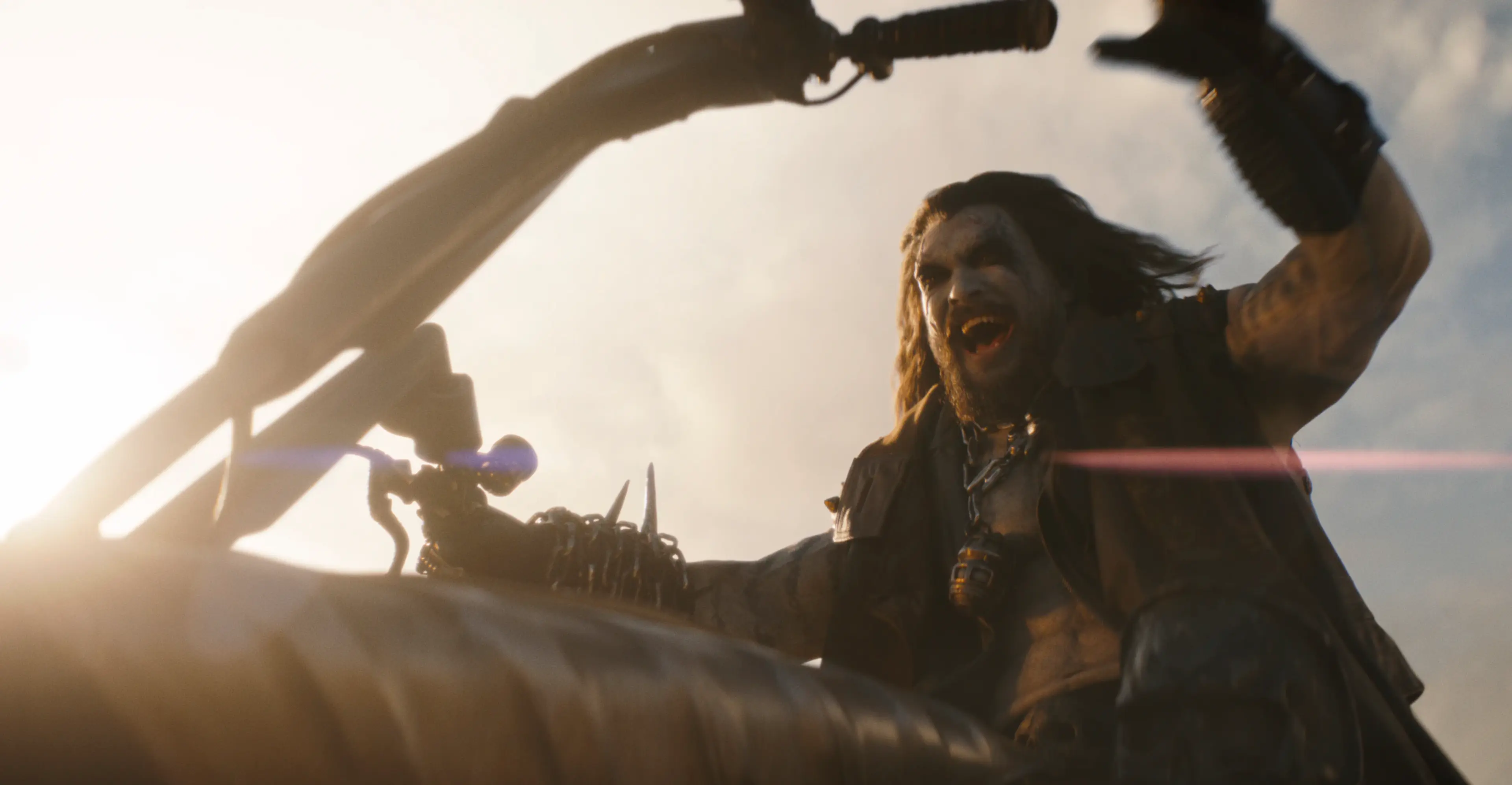 Jason Momoa as Lobo grins beside a mounted weapon.