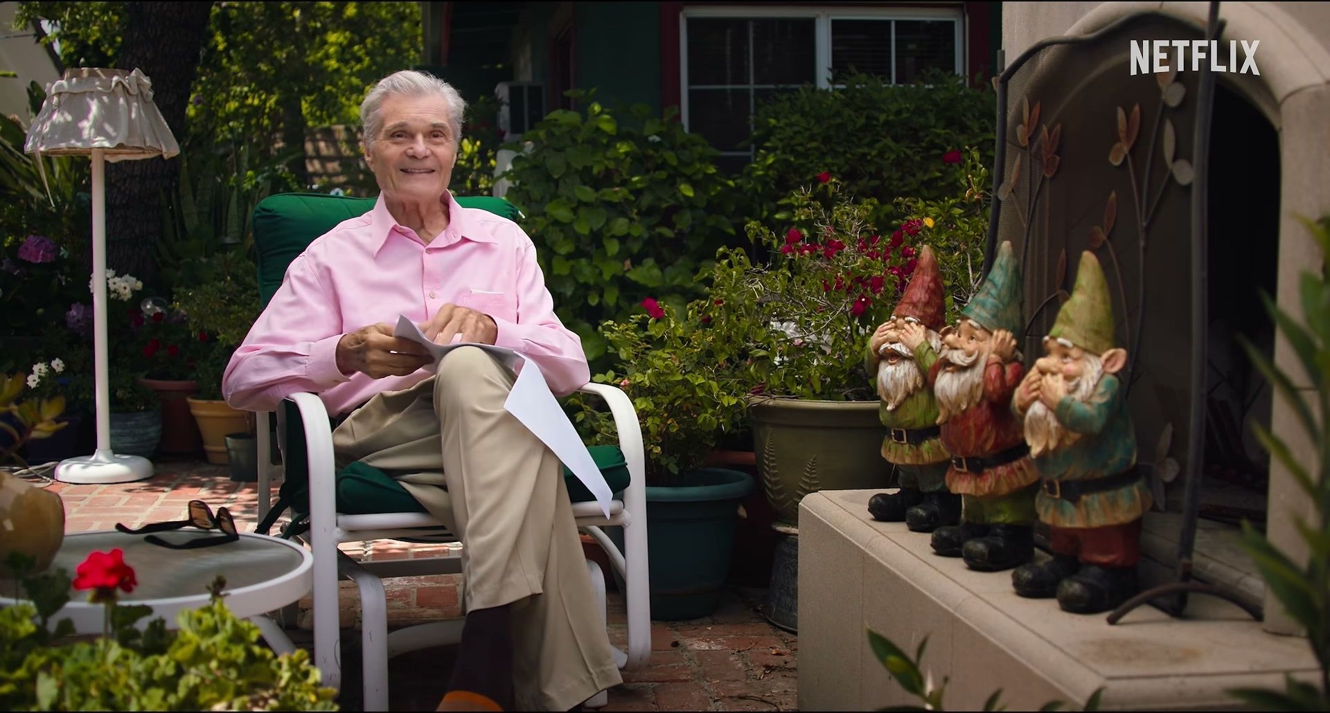 Martin Mull speaks while seated outdoors in a pink shirt