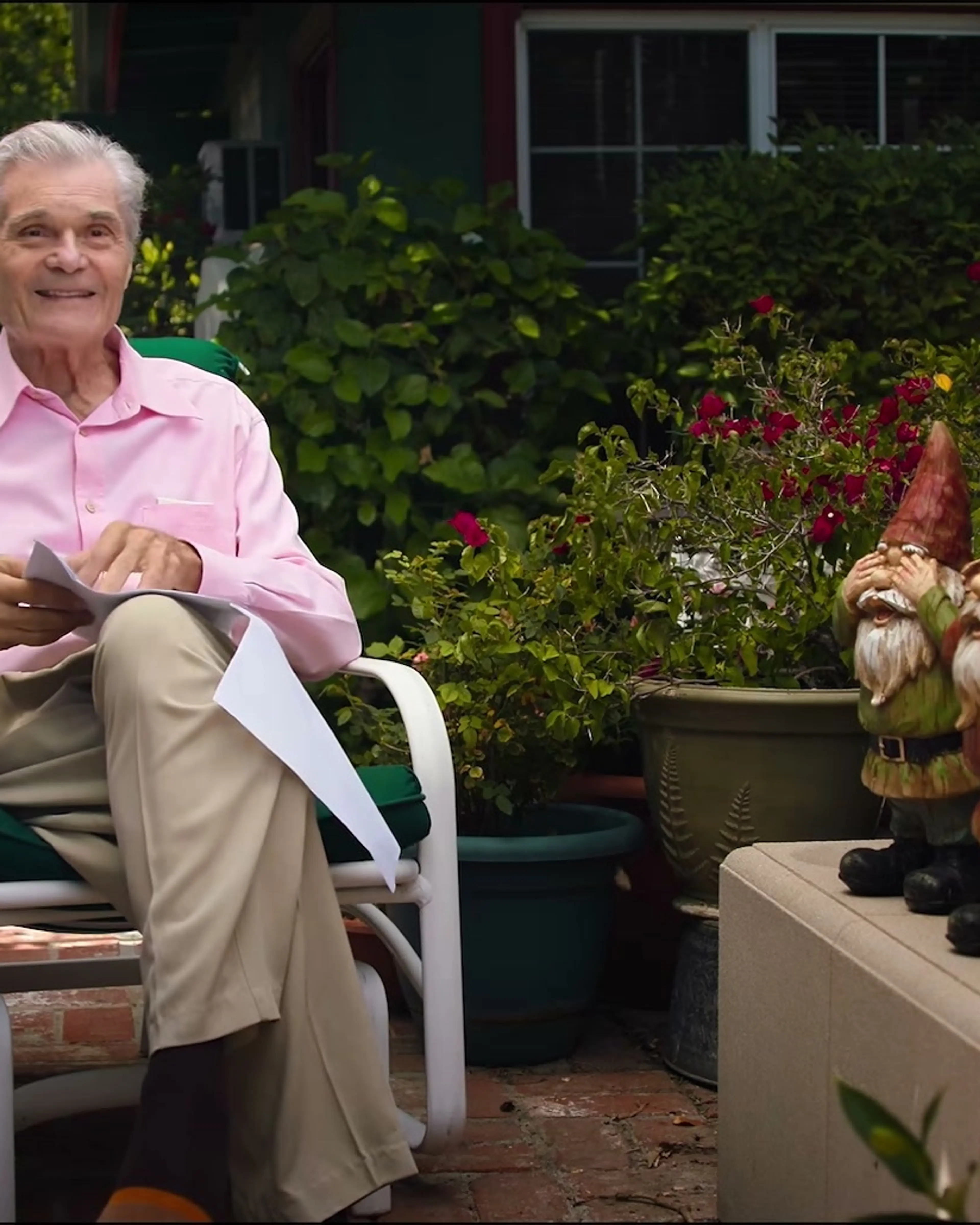 Martin Mull speaks while seated outdoors in a pink shirt