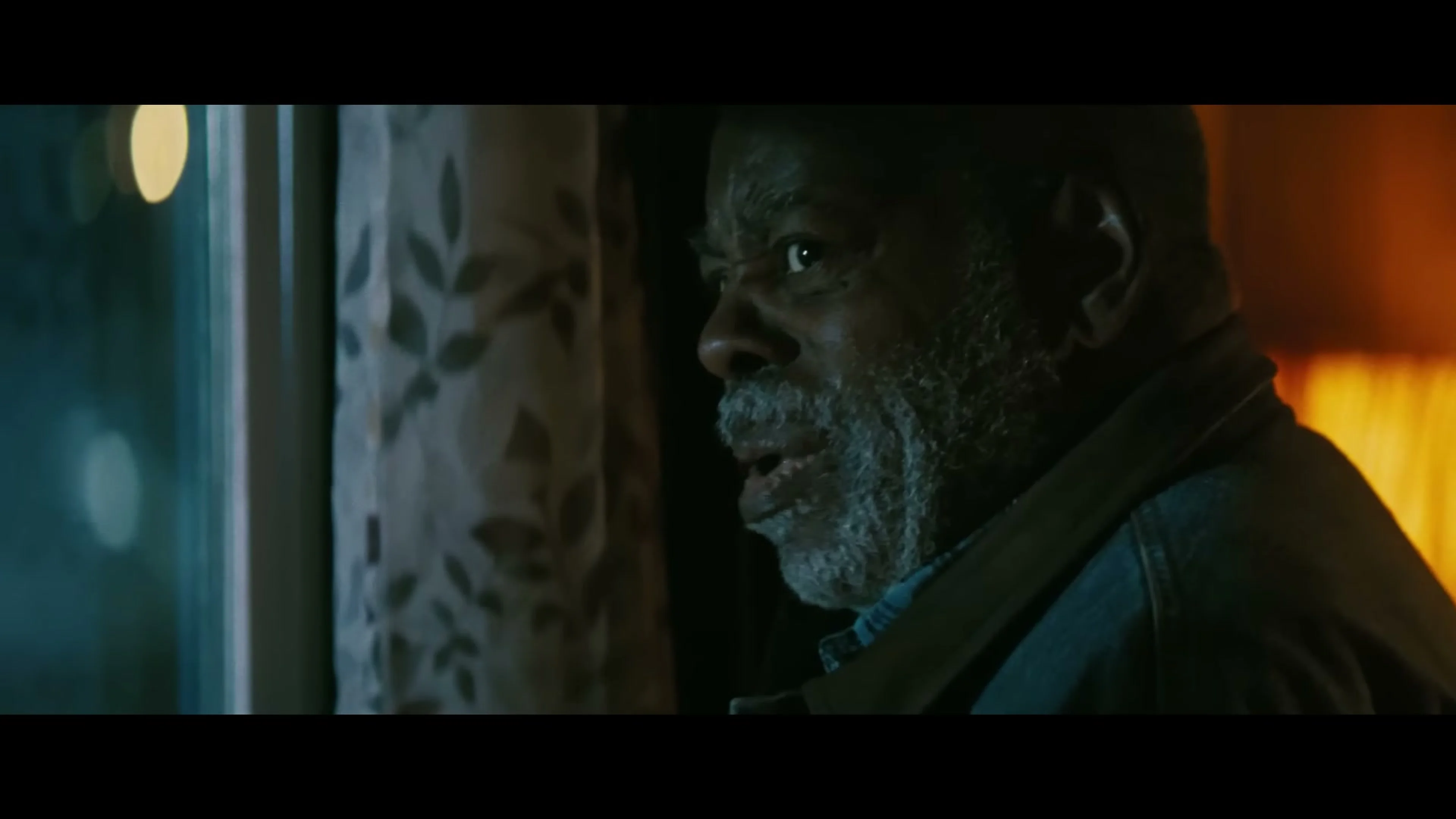 Reginald VelJohnson as Josiah looks through a doorway in Onslaught.