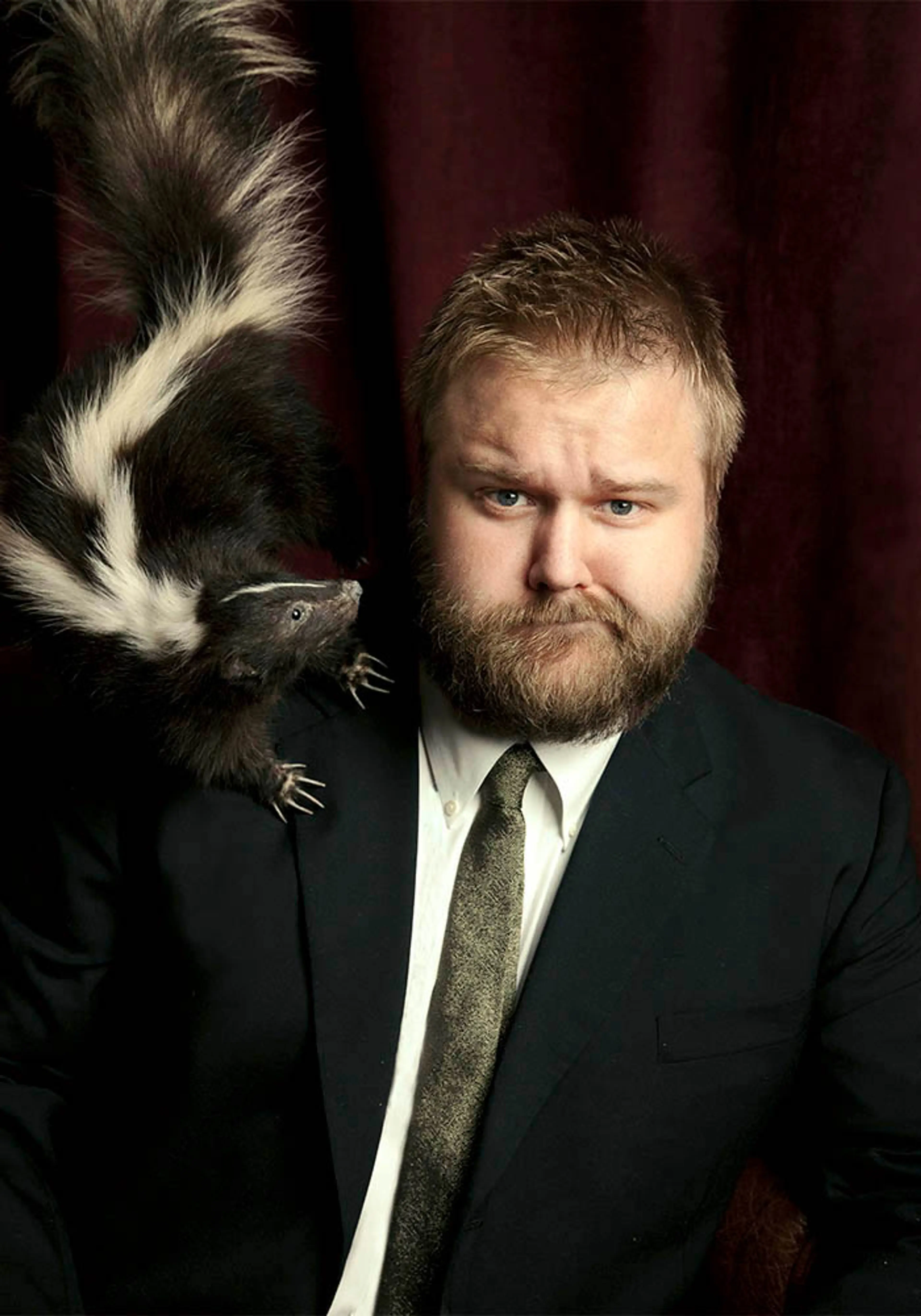 The Walking Dead creator Robert Kirkman poses beside a skunk prop.